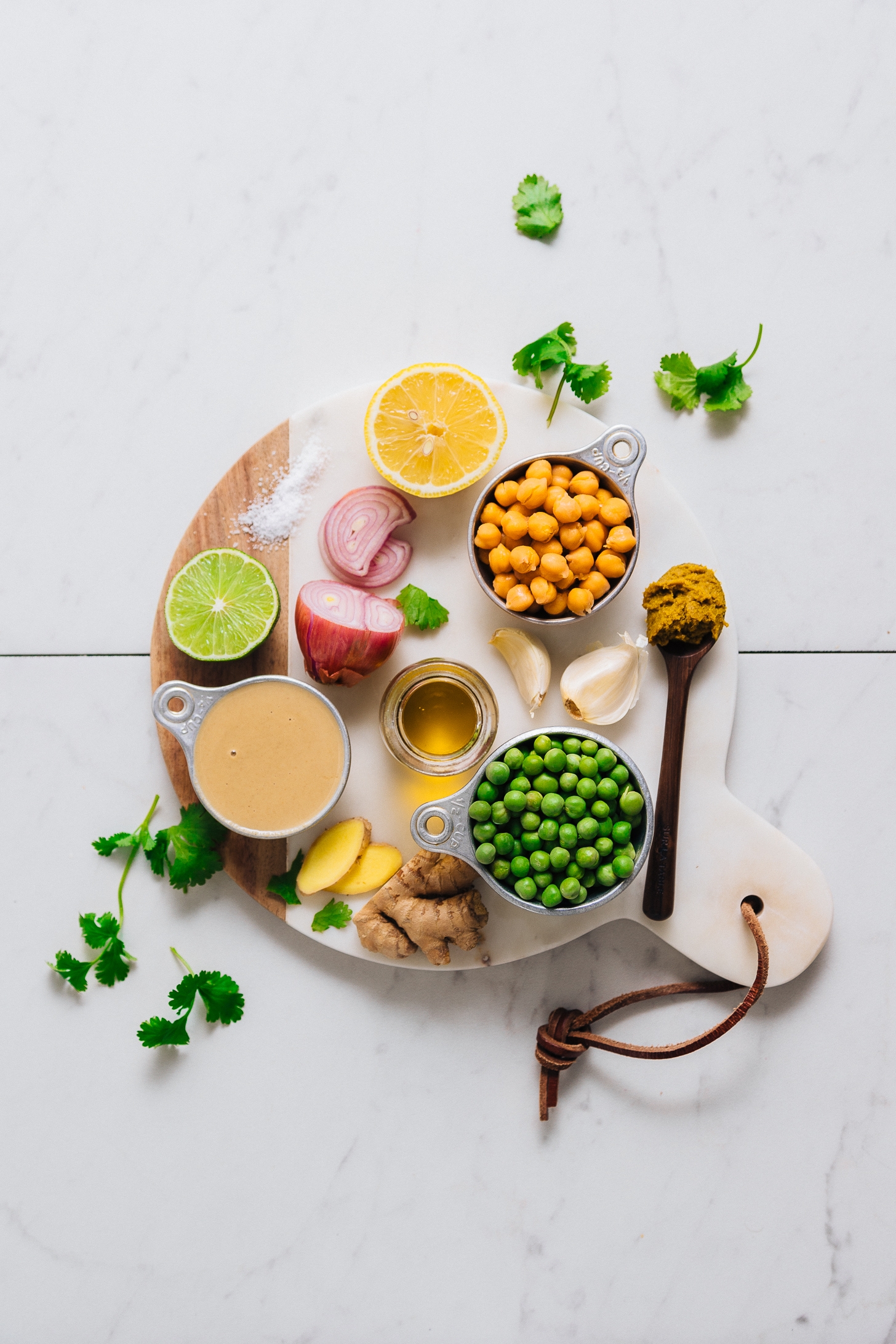 Wood and marble cutting board filled with ingredients for making our flavorful Green Pea Curry Hummus recipe
