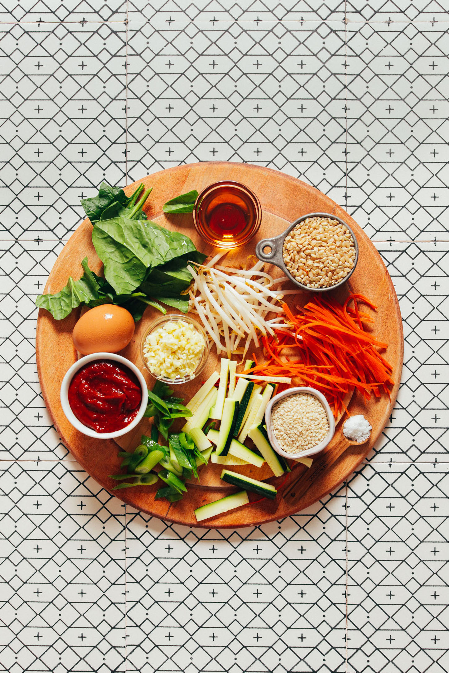 Wood cutting board with brown rice, vegetables, and an egg ready to show How to Make Korean Bibimbap