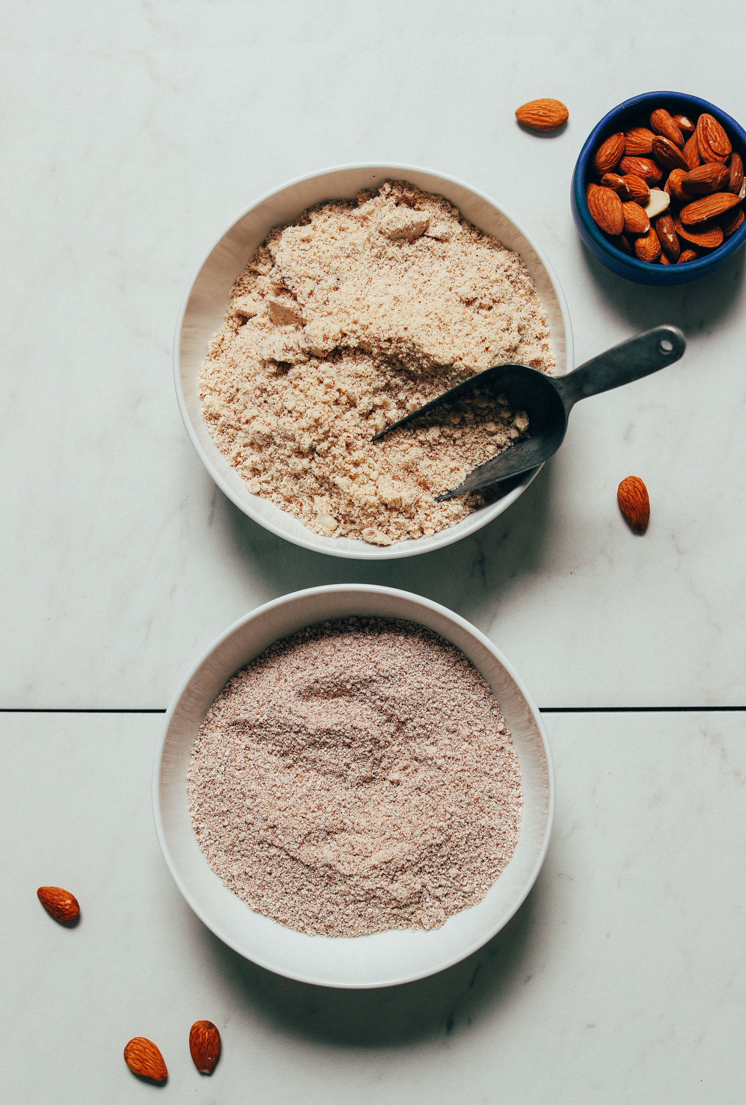 Bowls of almonds and almond meal made from pulp and raw almonds