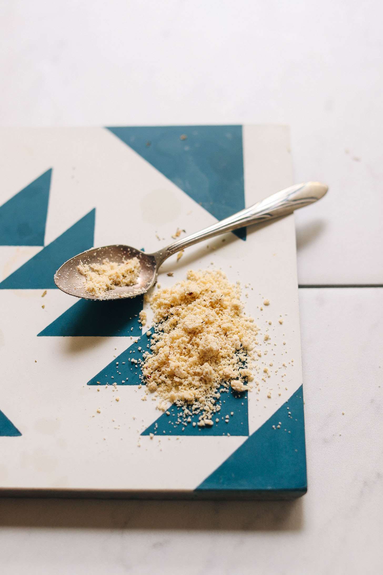 Spoonful of yeast-free Vegan Cashew Parmesan on a blue and white tile