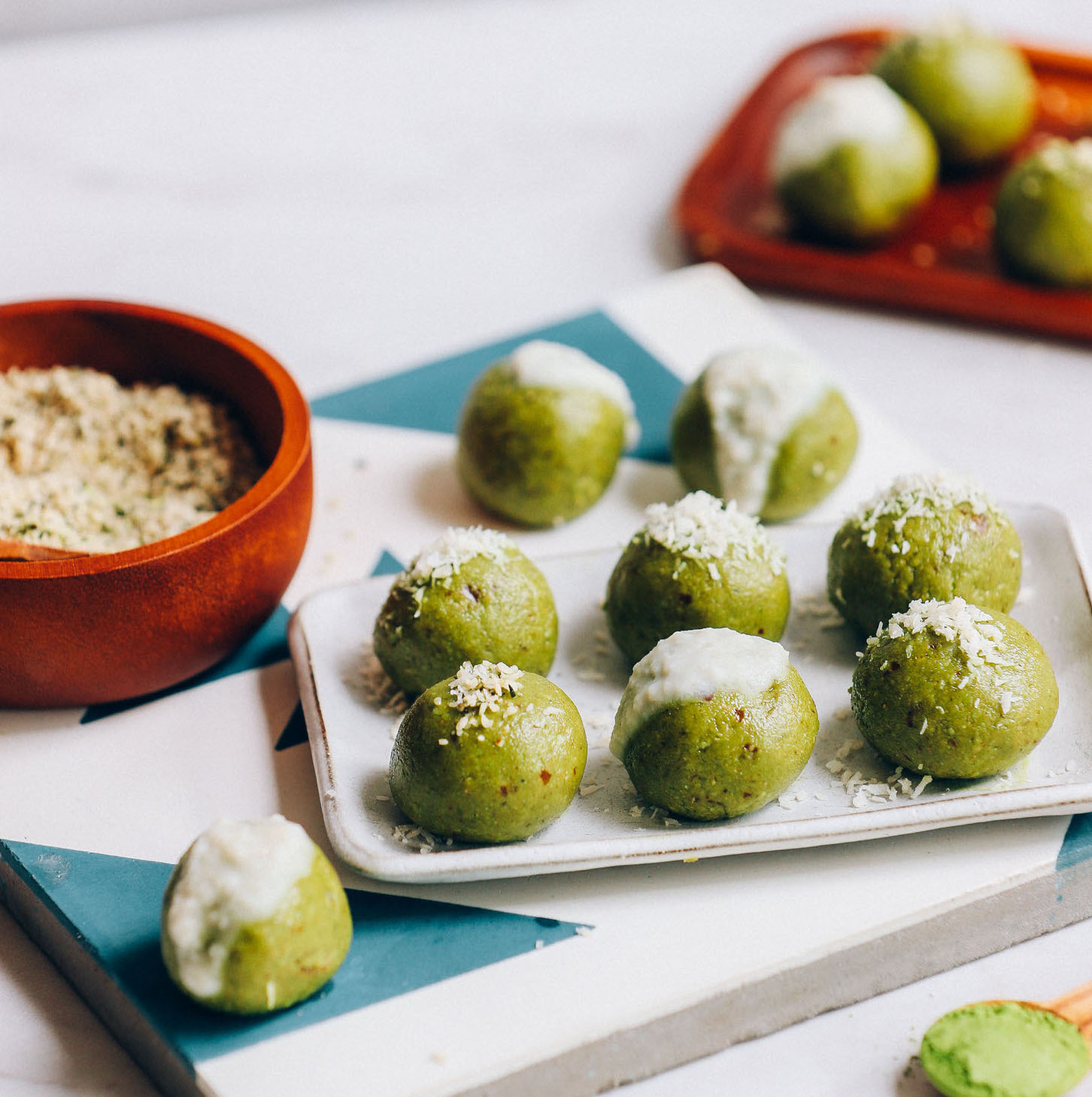 Tray of low sugar, date-sweetened Matcha Bliss Balls beside a bowl of hemp seeds
