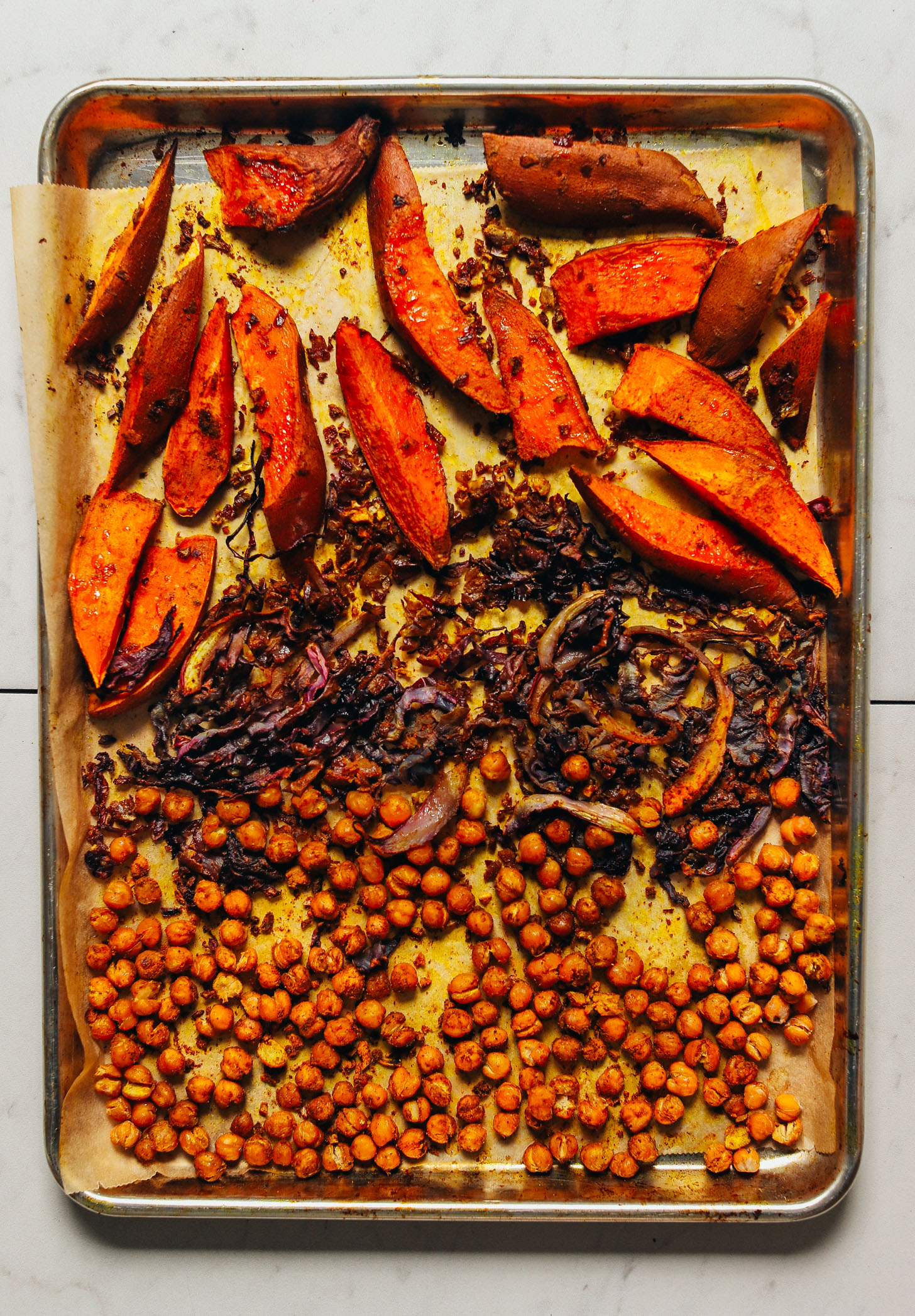 Baking sheet filled with freshly roasted cabbage, chickpeas, and sweet potatoes for a simple vegan Sheet Pan Dinner