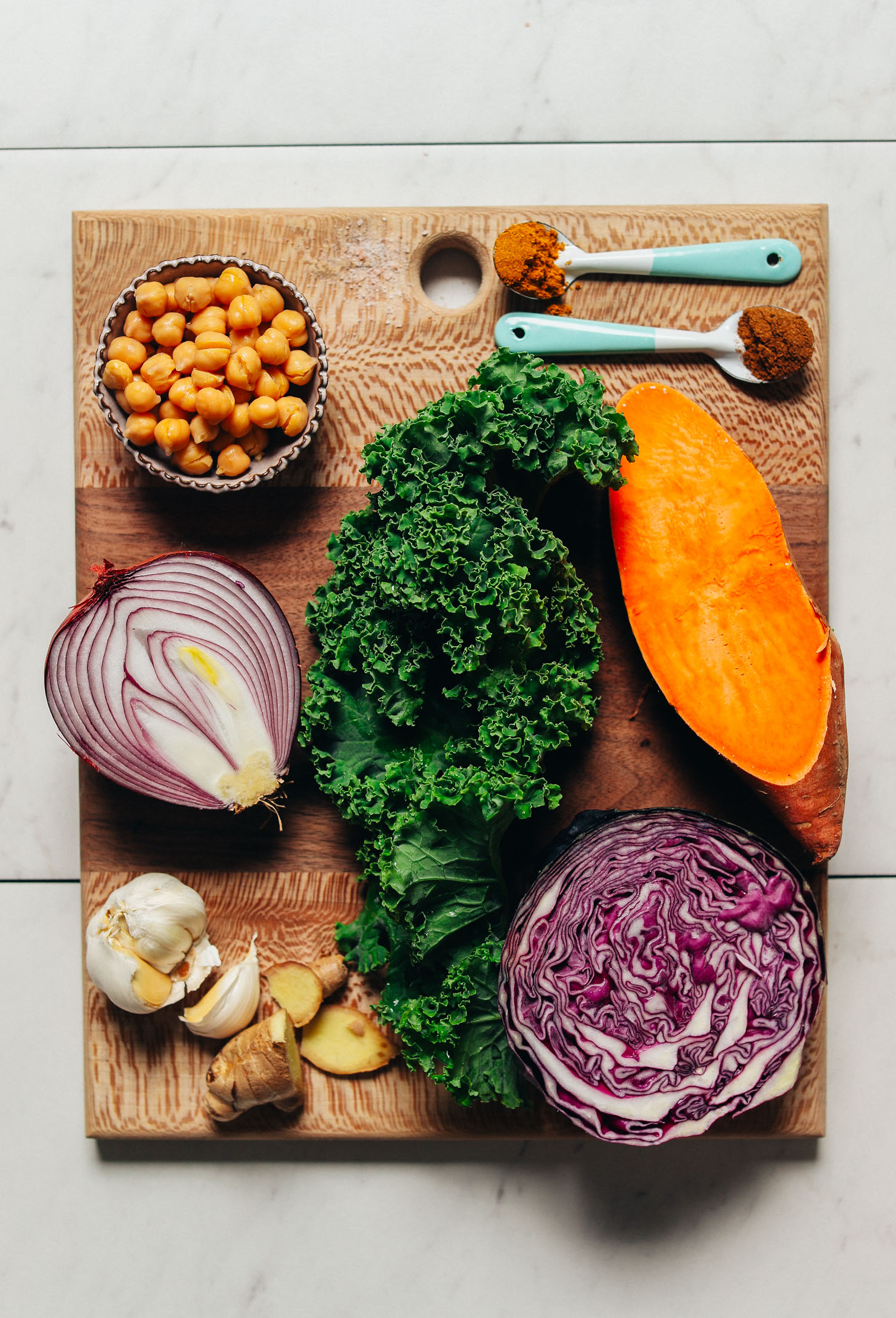 Wood cutting board filled with ingredients for making our Curried Sweet Potato Sheet Pan Dinner