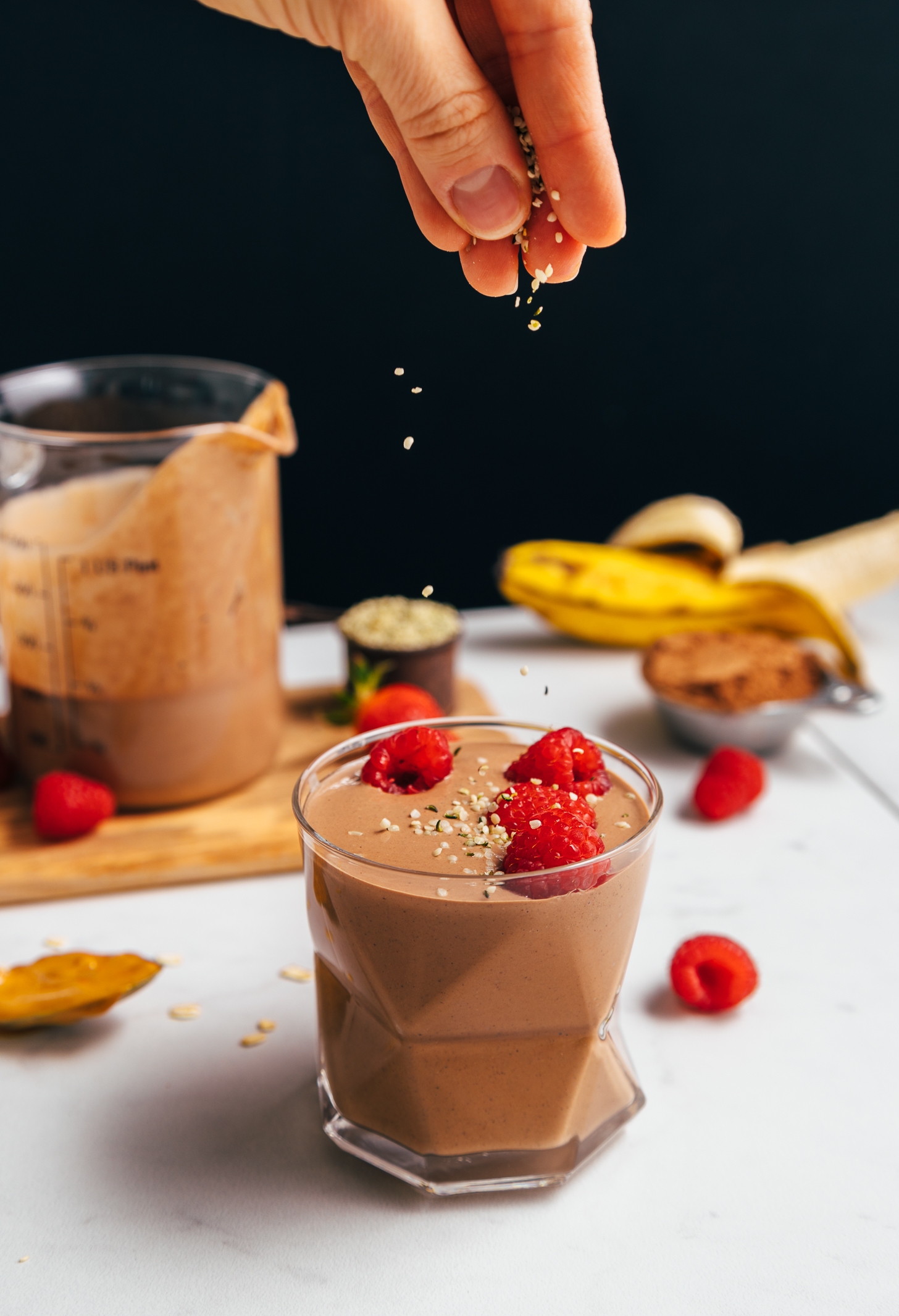 Sprinkling hemp seeds onto a glass of Protein Powder-Free Chocolate Shake