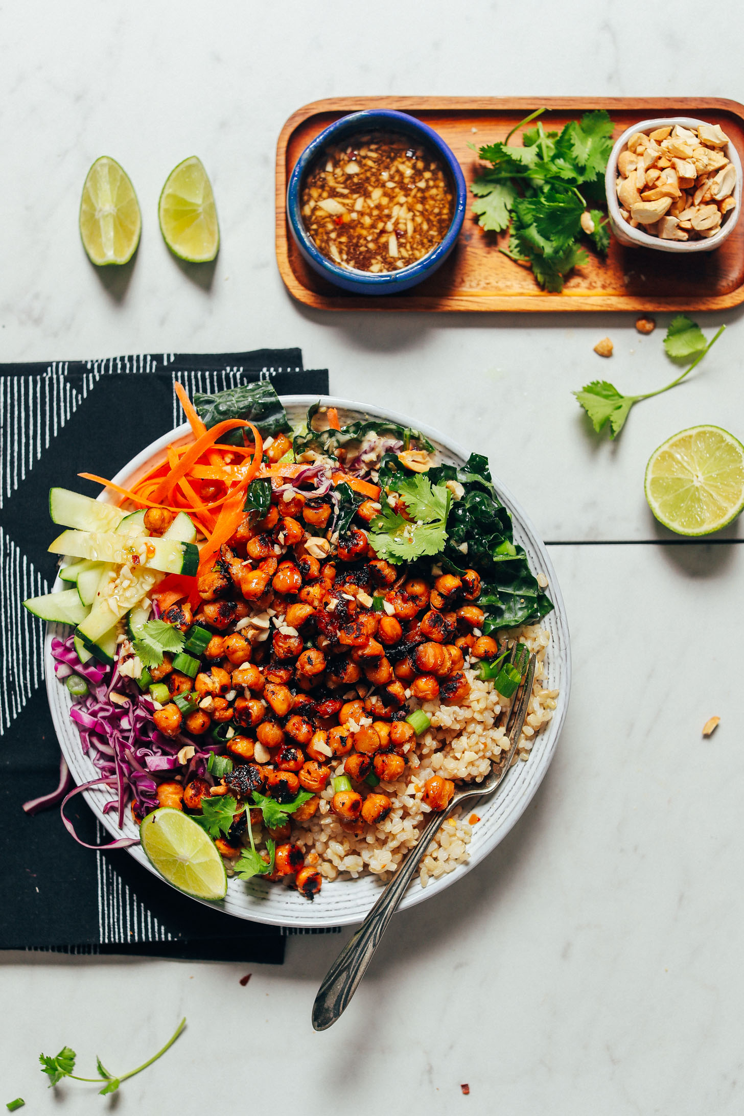 Crispy Miso Chickpea Bowl beside serving ingredients including cilantro, dressing, cashews, and lime