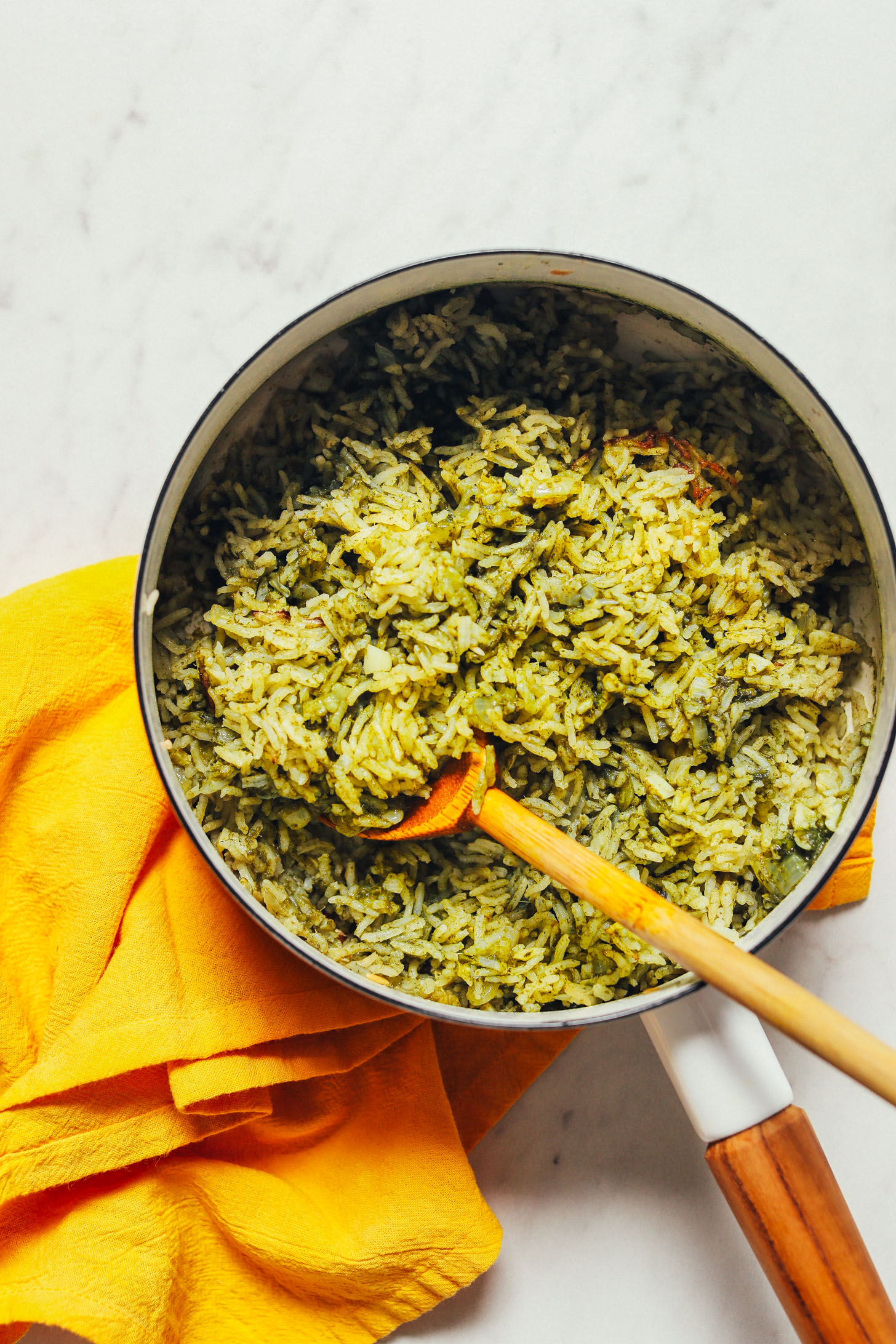 Wooden spoon resting in a pan of homemade Mexican-inspired Green Rice