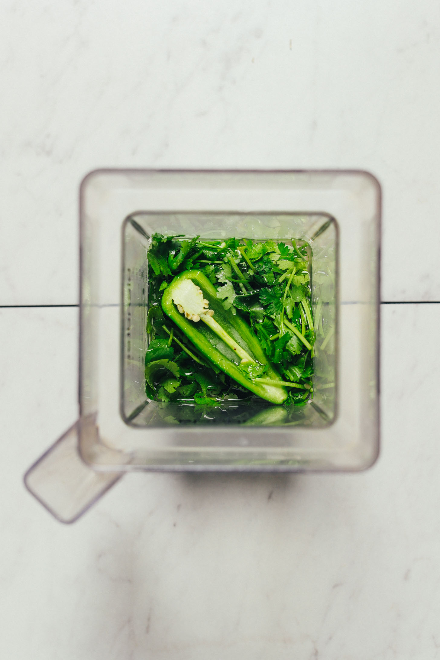 Blender filled with ingredients for making a green sauce for our Green Rice recipe