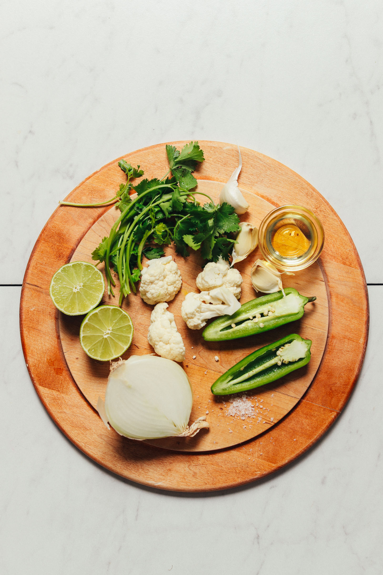 Wood cutting board with ingredients for making our Cauliflower Green Rice recipe