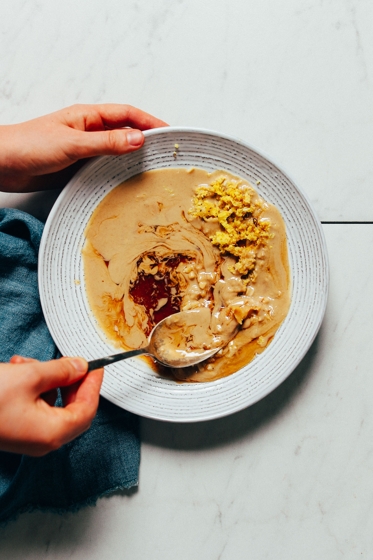 Stirring a bowl of our Ginger Garlic Miso Tahini Dressing