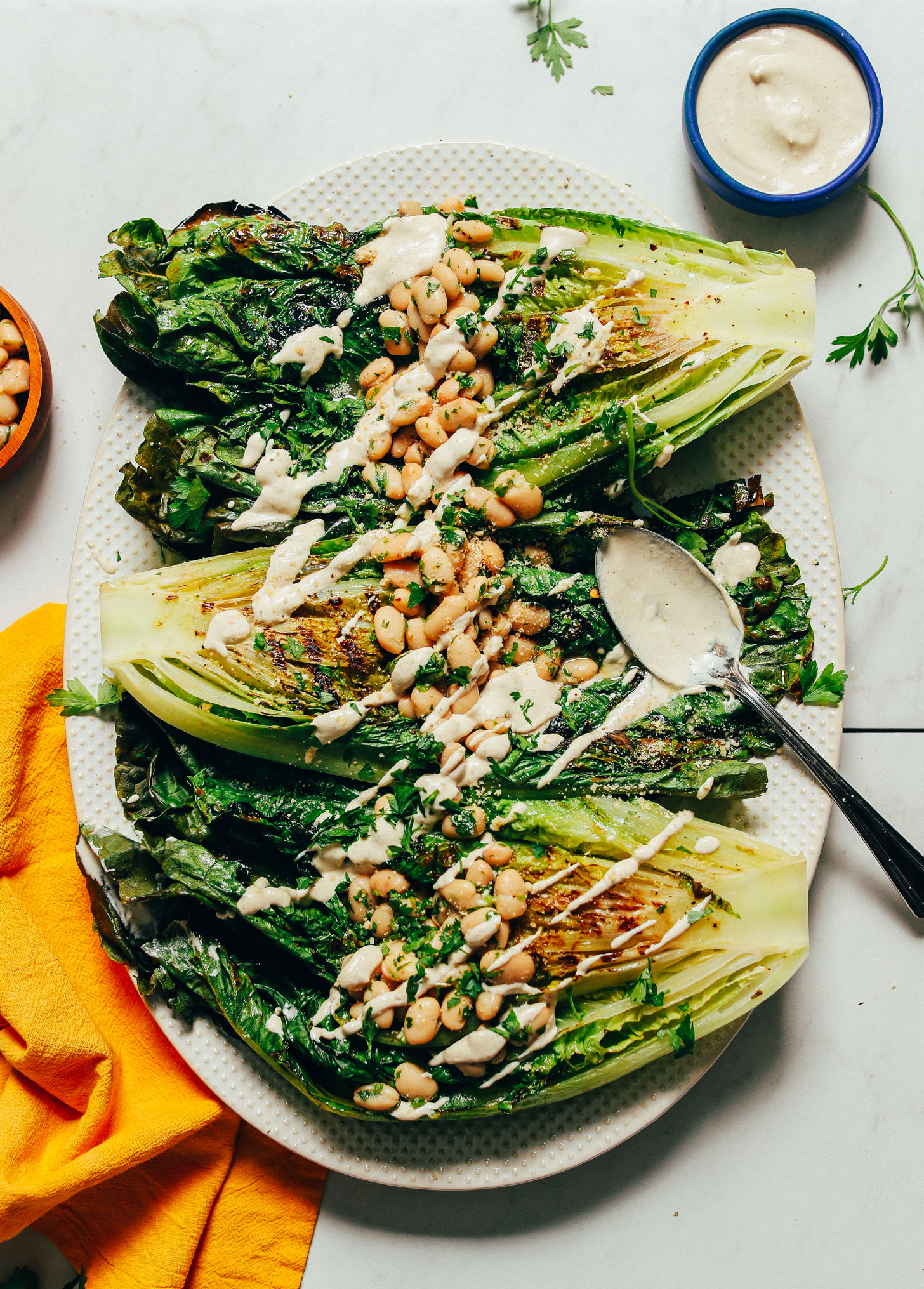 Platter of broiled romaine topped with Herbed Beans and drizzled with Vegan Caesar Dressing