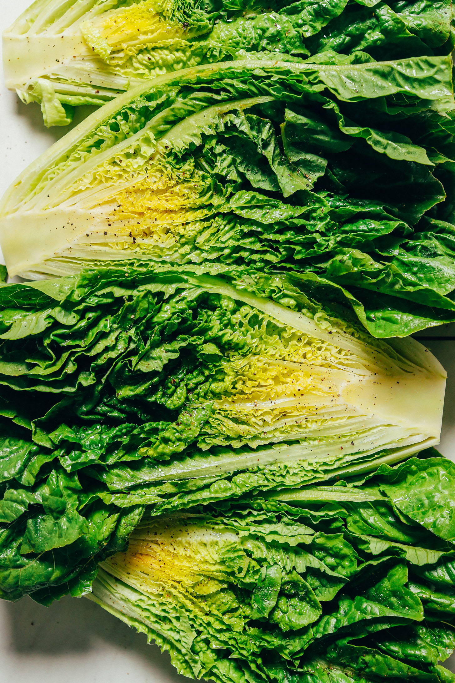 Halved heads of romaine lettuce sprinkled with black pepper