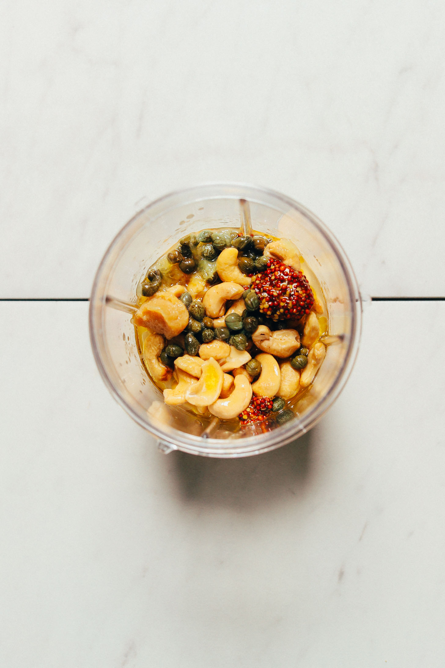 Small blender filled with ingredients for making our egg-free Caesar Dressing recipe