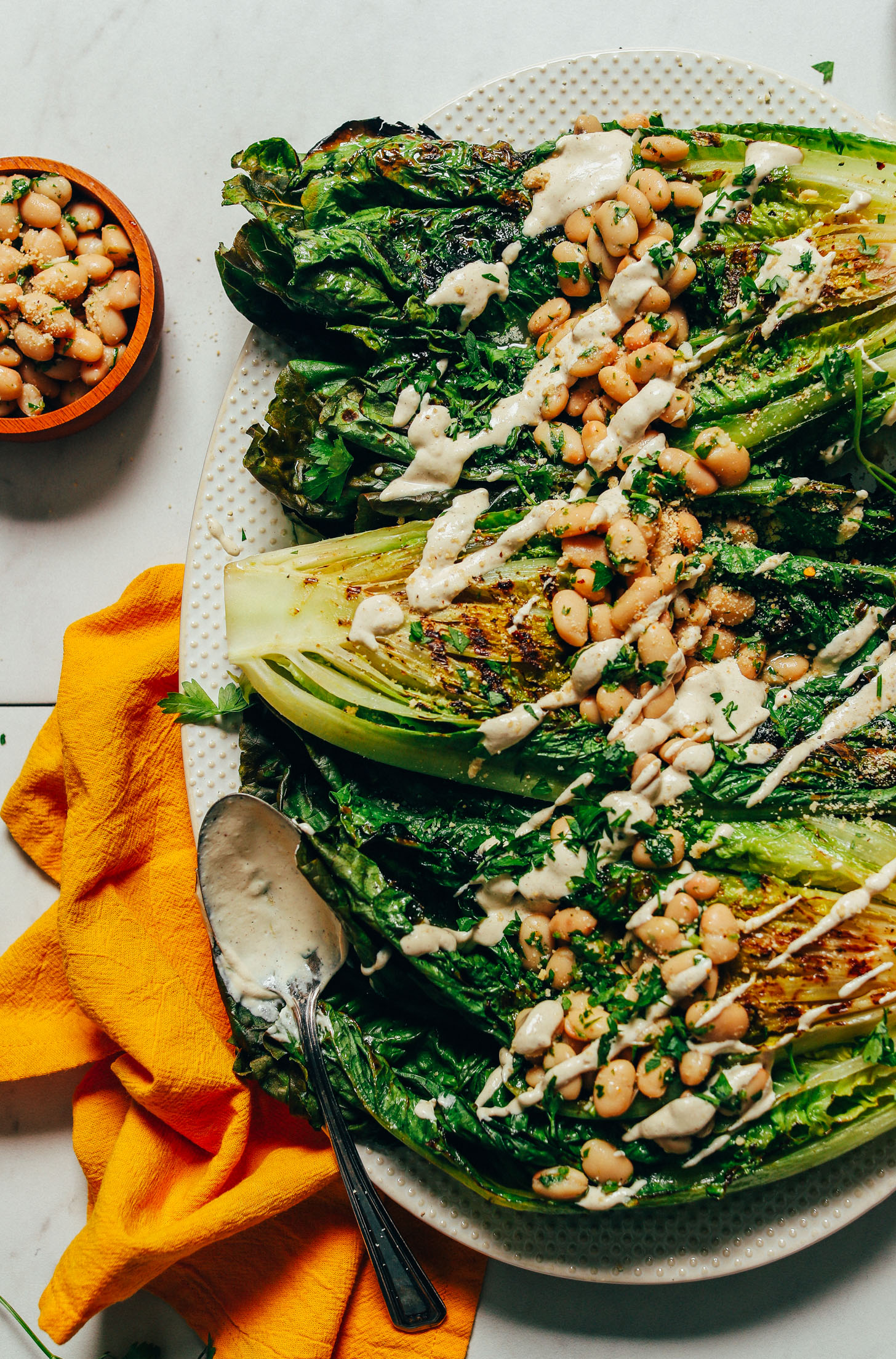 Large platter of Grilled Romaine Salad with Lemon Herbed Beans and a drizzle of Quick Caesar Dressing