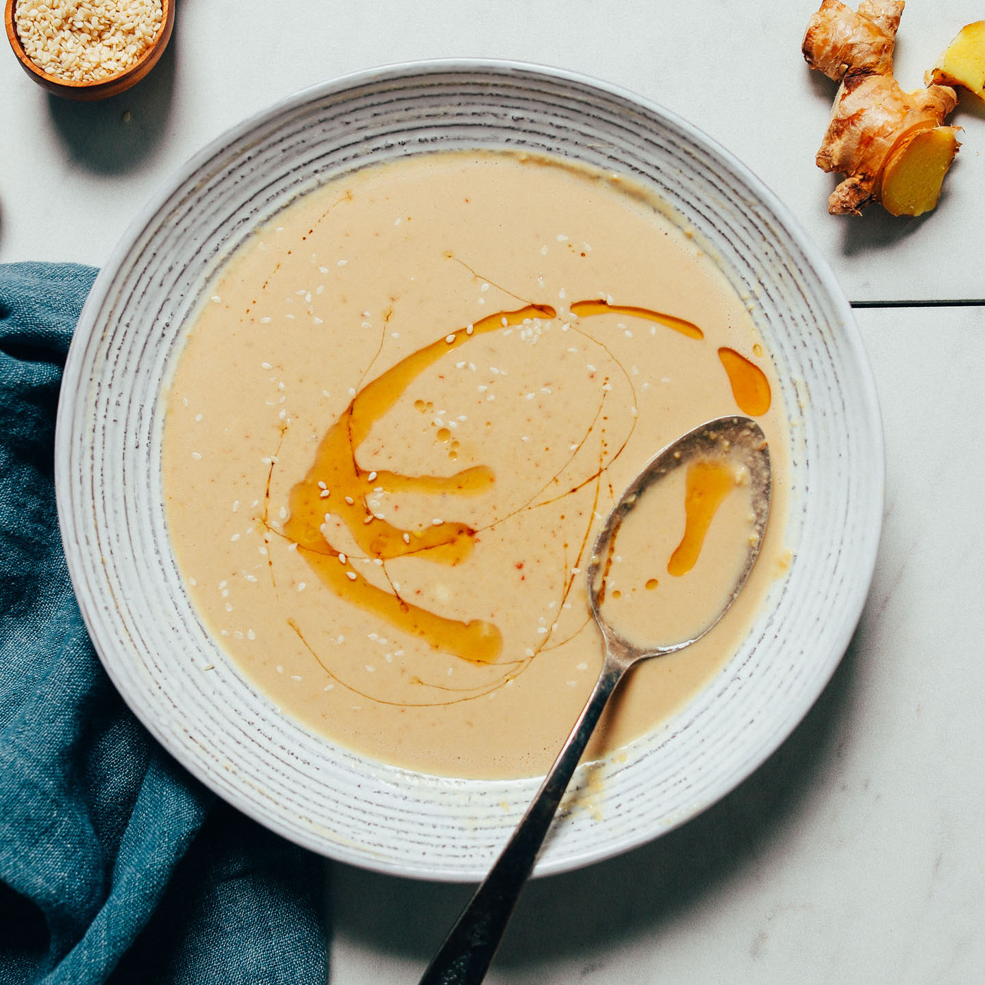 Bowl of Ginger Garlic Miso Tahini Dressing with a swirl of toasted sesame oil