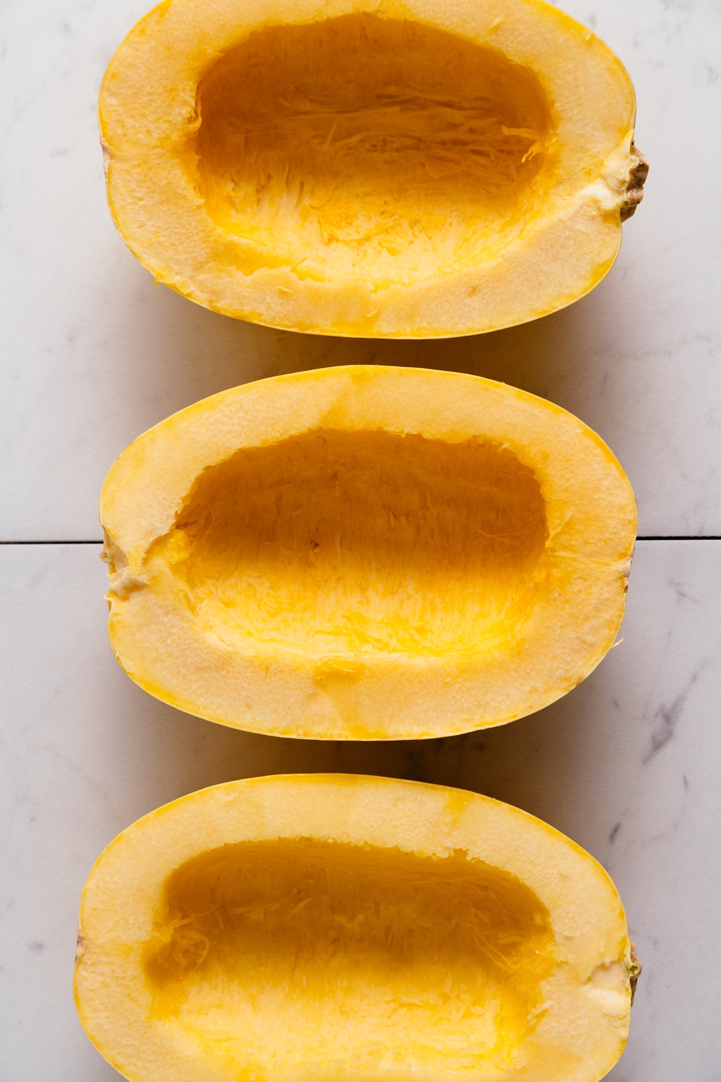 Three halves of spaghetti squash with seeds removed