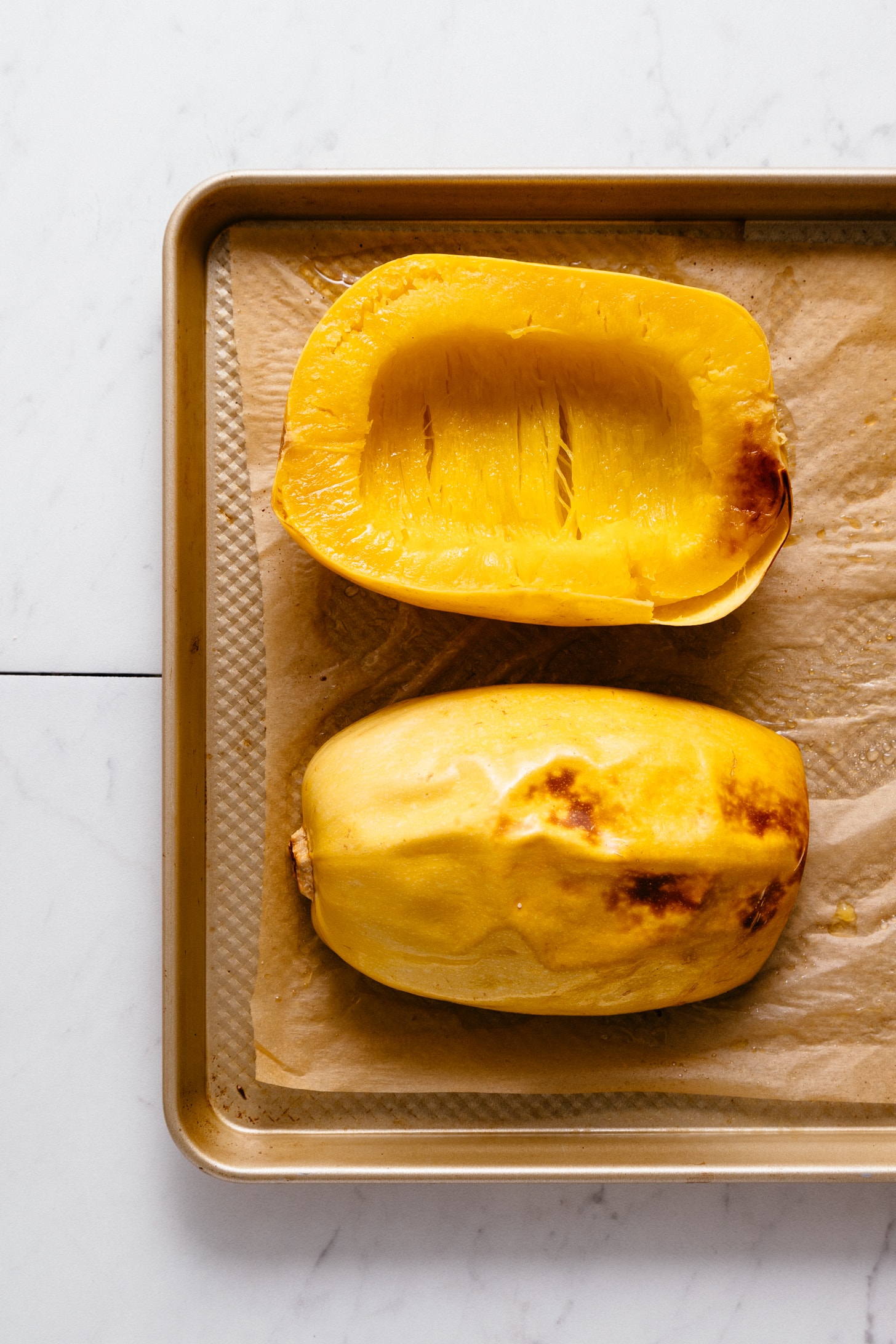 Halved roasted spaghetti squash on a baking sheet