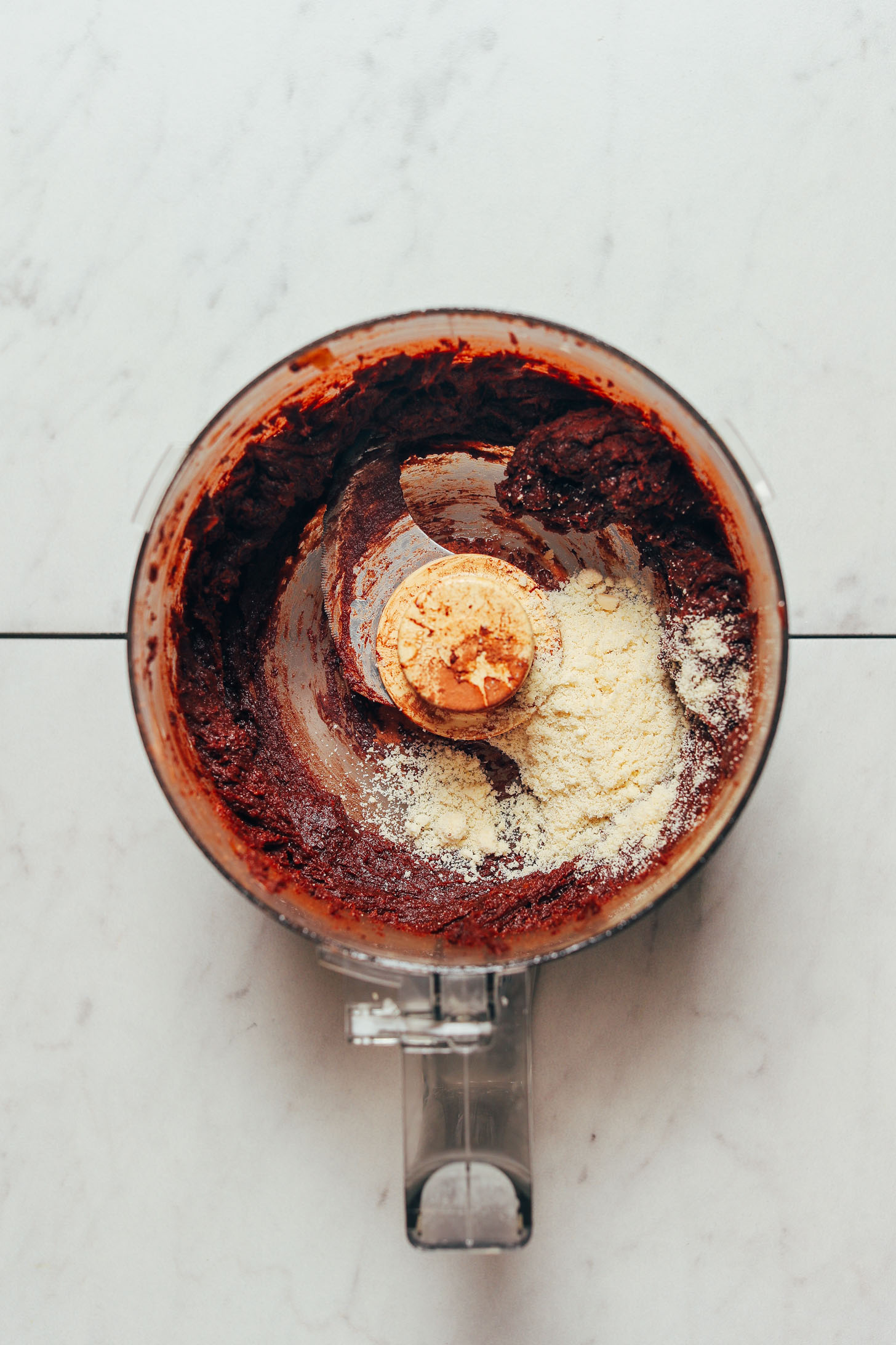 Almond flour in a food processor with freshly blended ingredients for making simple Vegan Chocolate Truffles sweetened with dates