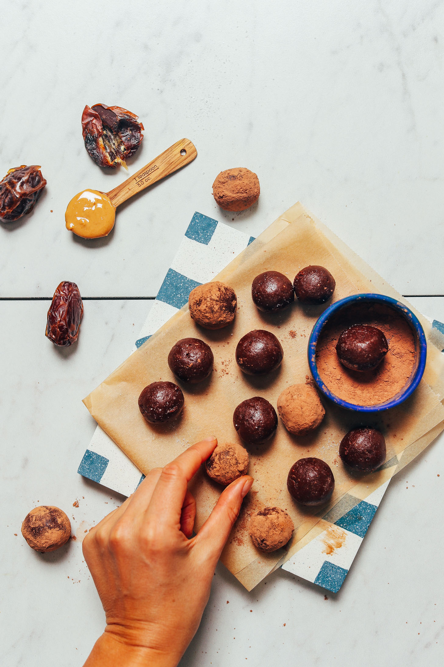 Placing a date-sweetened Vegan Chocolate Truffle onto a parchment-lined tile
