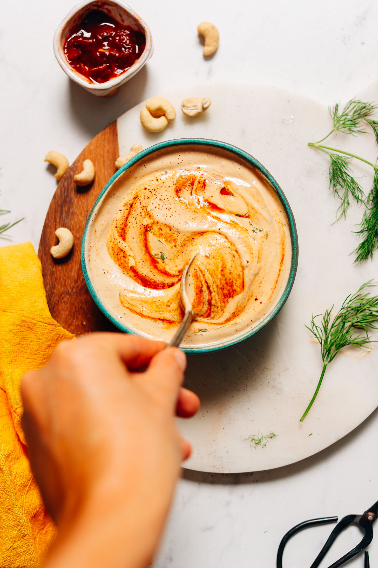 Stirring a bowl of Vegan Chipotle Ranch Dressing made with cashews