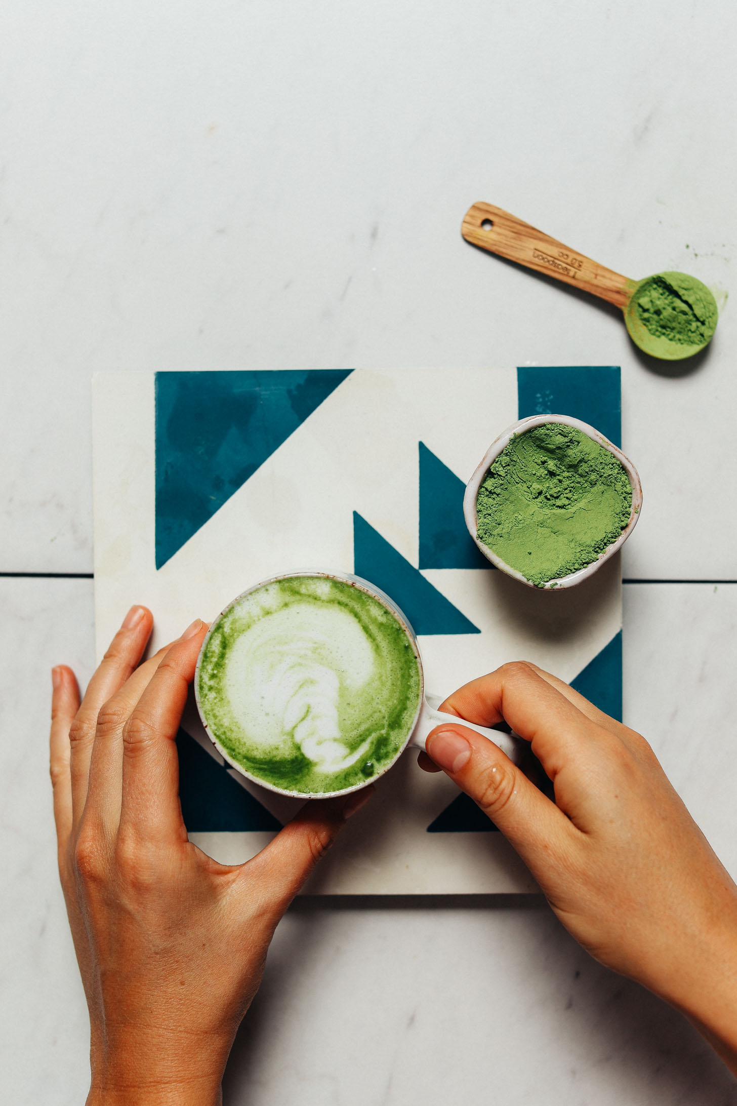 Holding a mug of a homemade Moringa Latte made with coconut milk