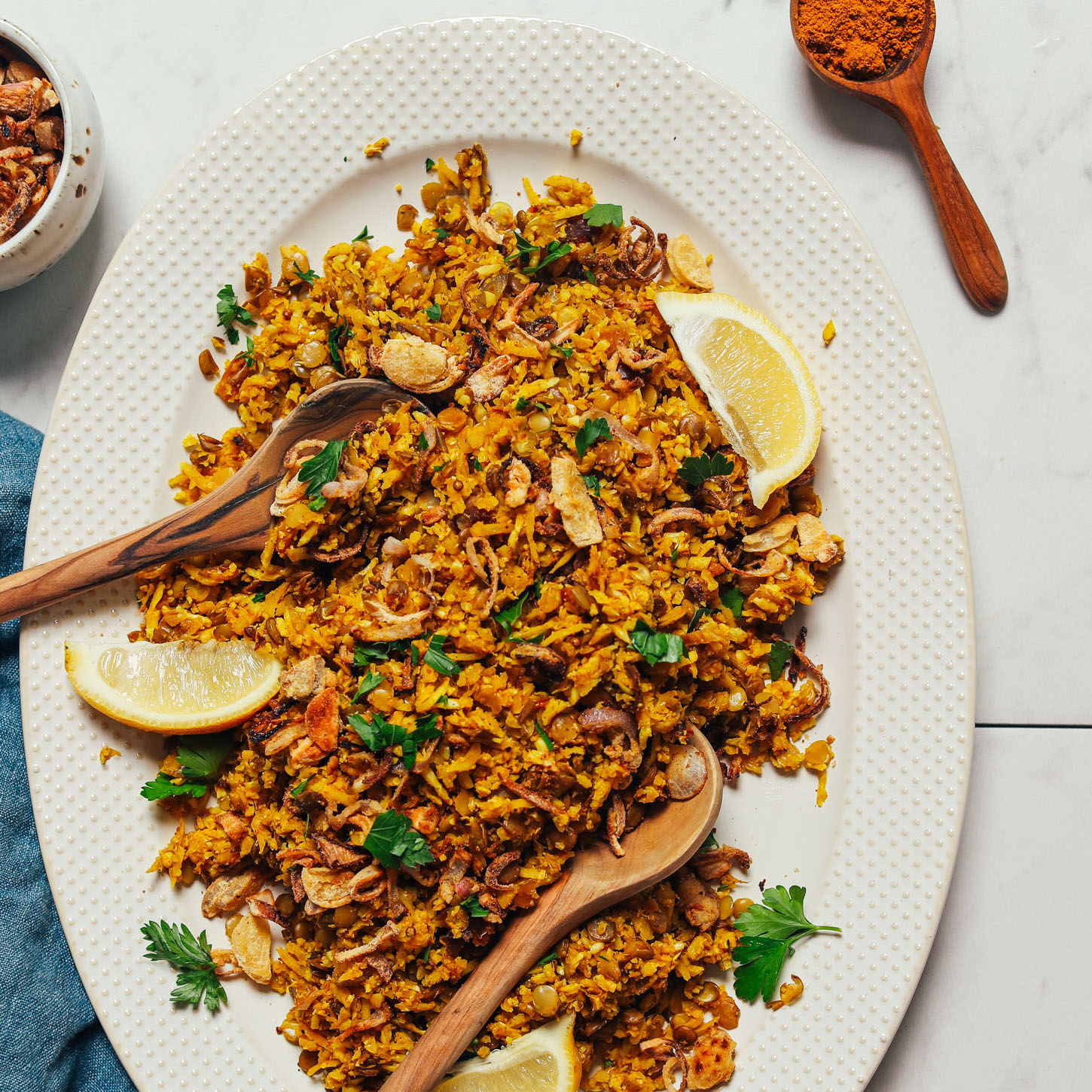 Lemon wedges and fresh cilantro on a platter of our Cauliflower Rice Mujadara recipe