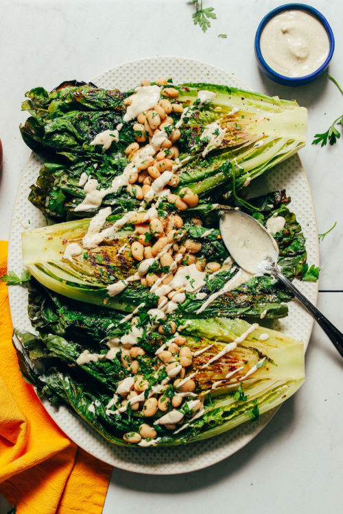 Platter of vegan Grilled Romaine Salad with Lemon Herbed Beans and Quick Caesar Dressing