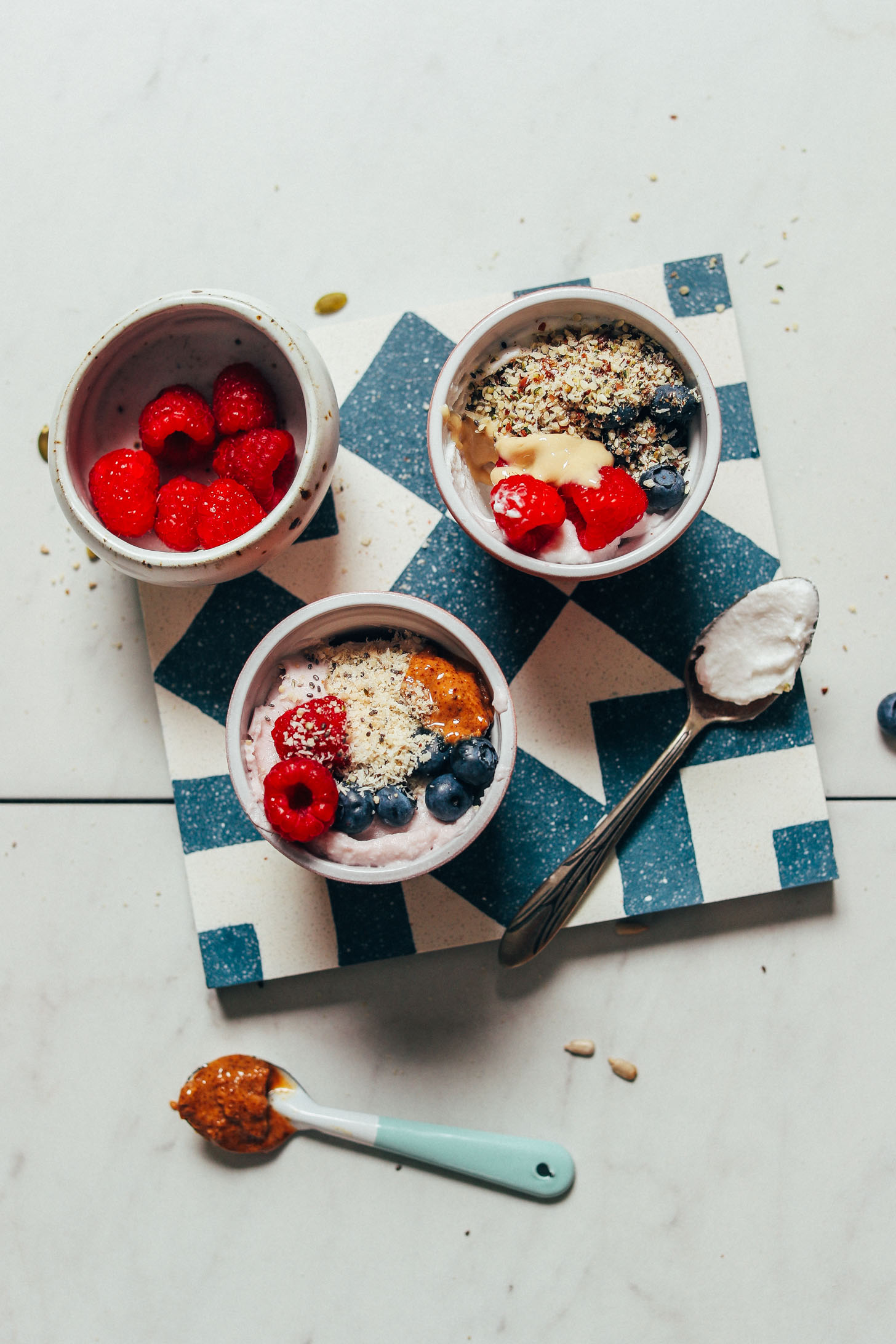 Bowls of dairy-free yogurt with fruit to show a recipe for how to use seed cycling mixes