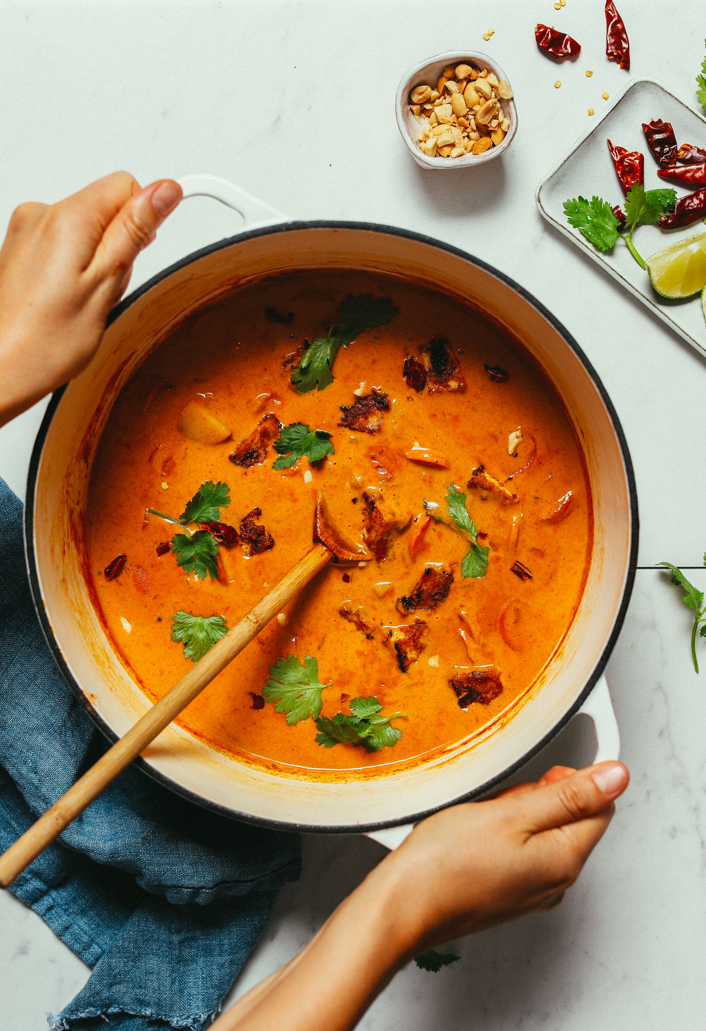 Holding the handles of a big pot of Massaman Curry made with peanuts and lime