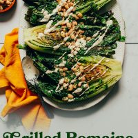 Platter of Grilled Romaine Salad topped with vegan caesar dressing and herbed white beans