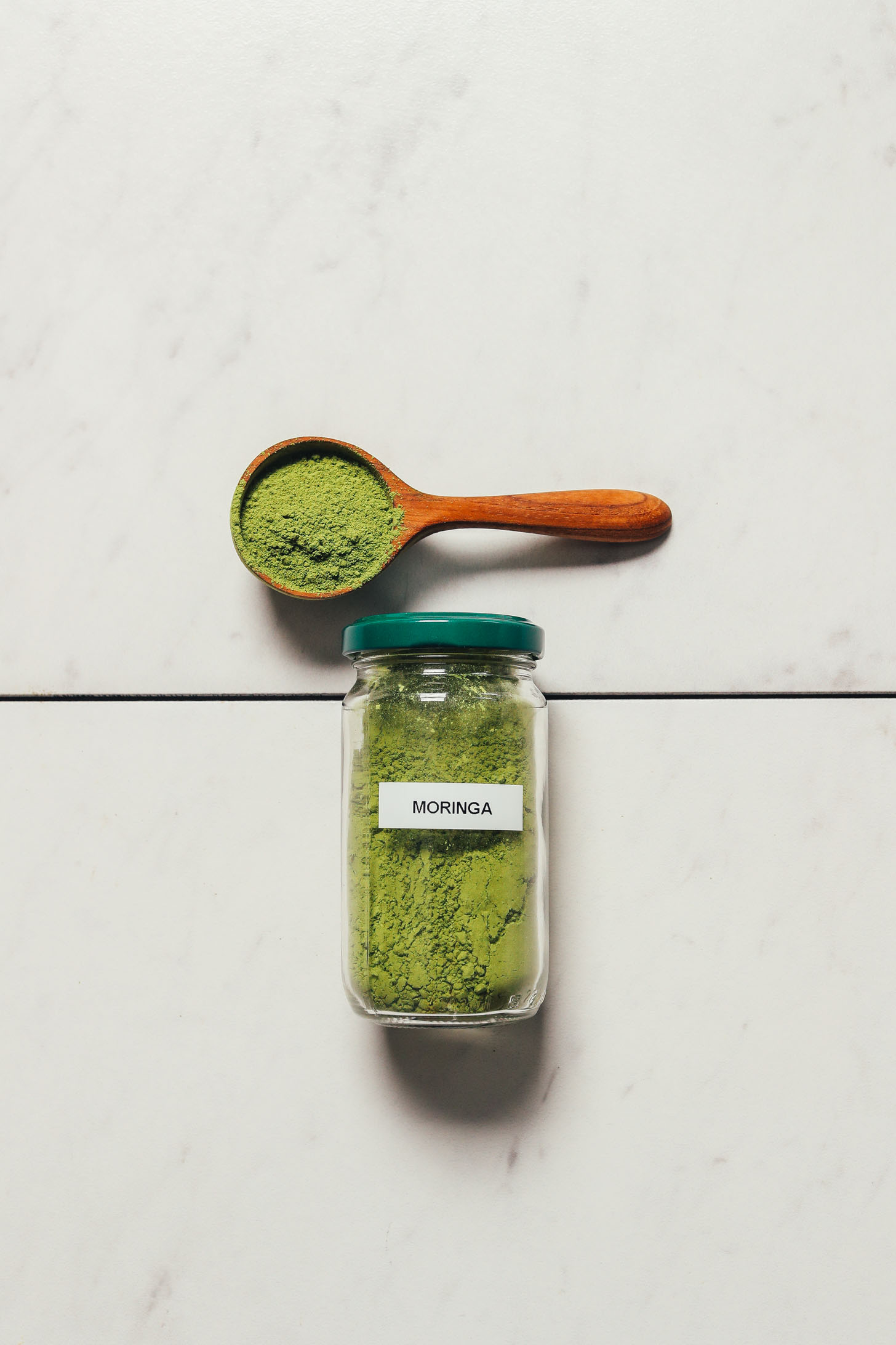 Jar and spoonful of Miracle Garden moringa powder for our top rated moringa powder