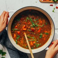 Holding a pot of Spiced Sweet Potato Lentil Soup made with green beans