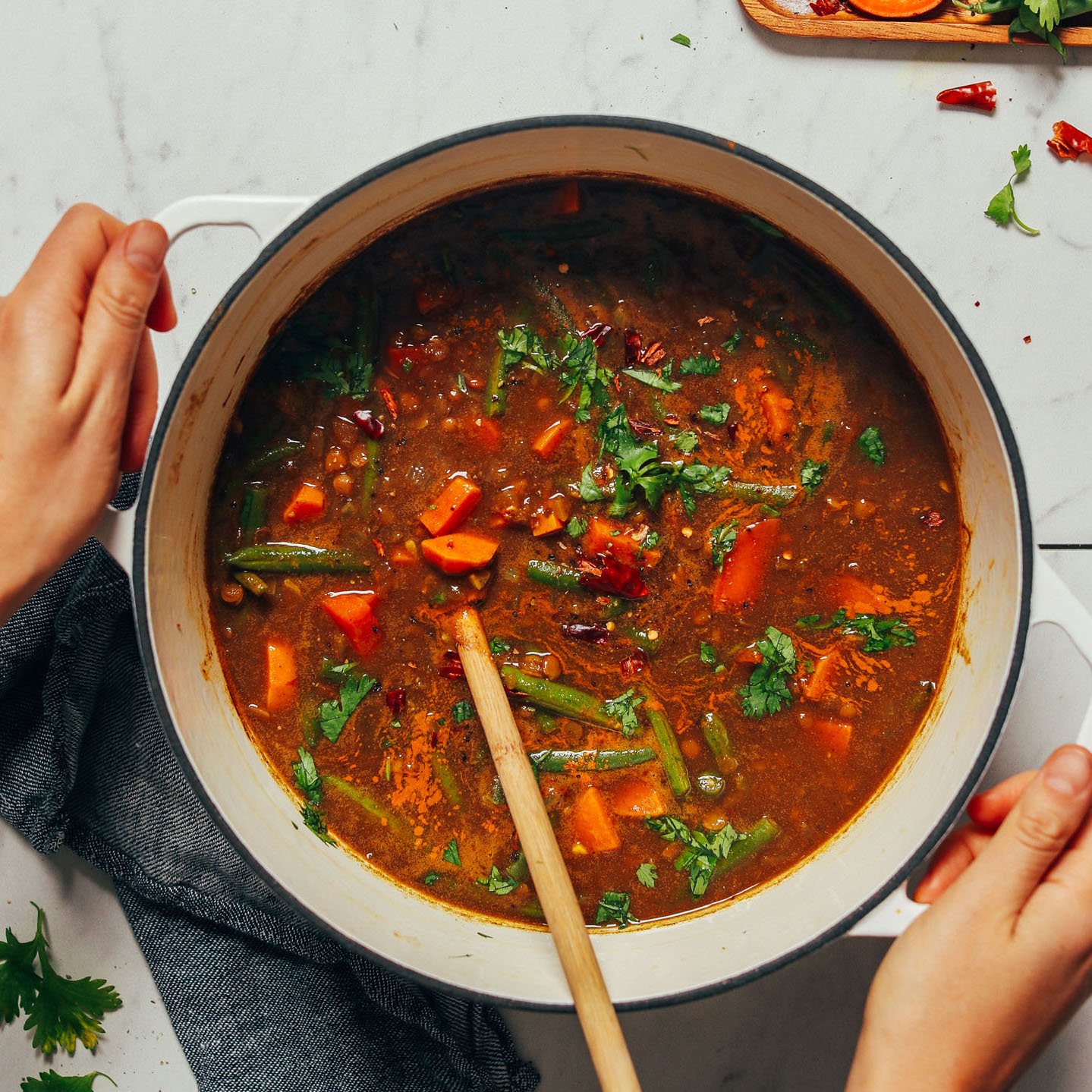 Holding a pot of Spiced Sweet Potato Lentil Soup made with green beans
