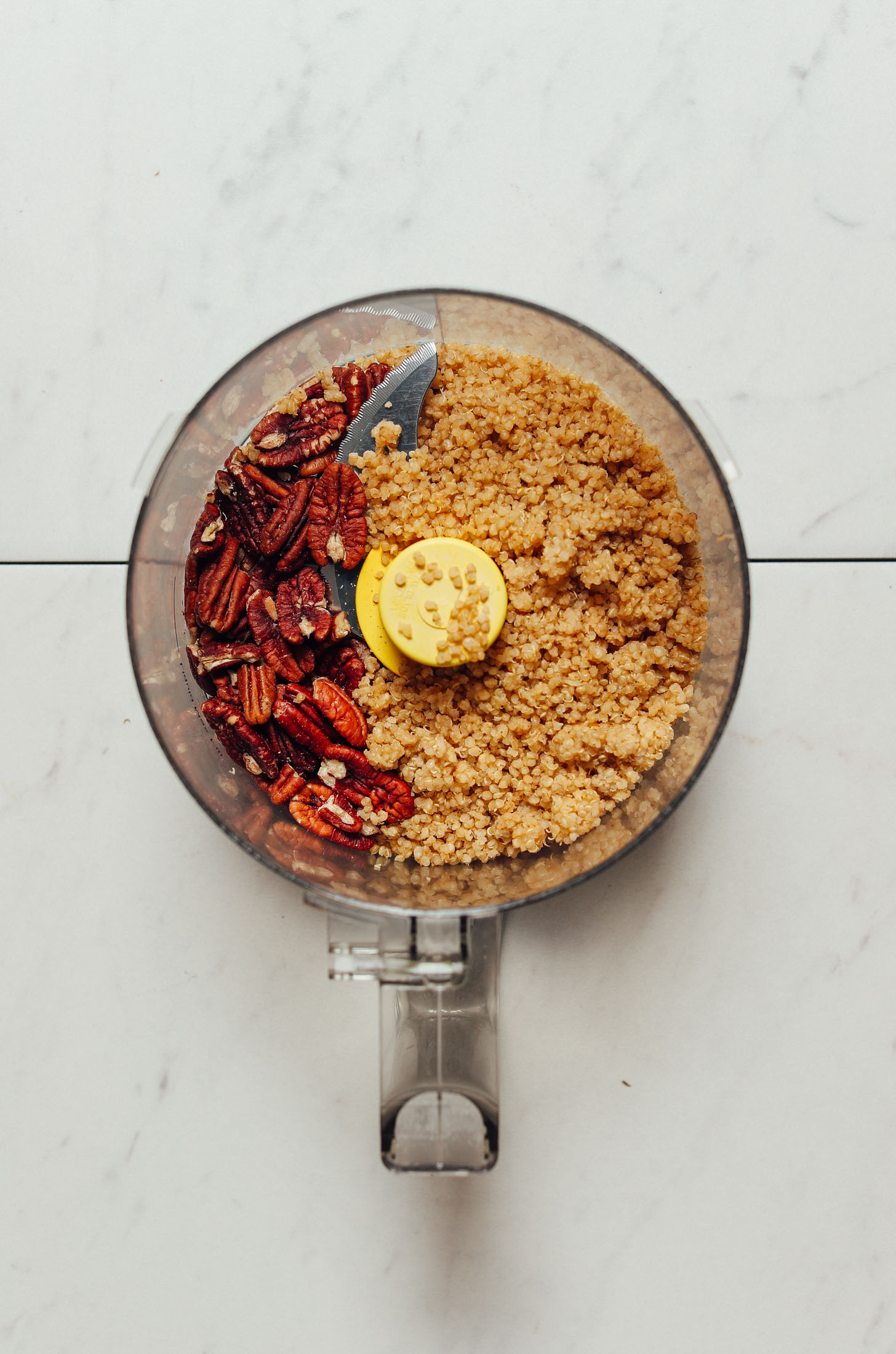 Food processor filled with pecans and quinoa for making simple homemade Vegan Sausages