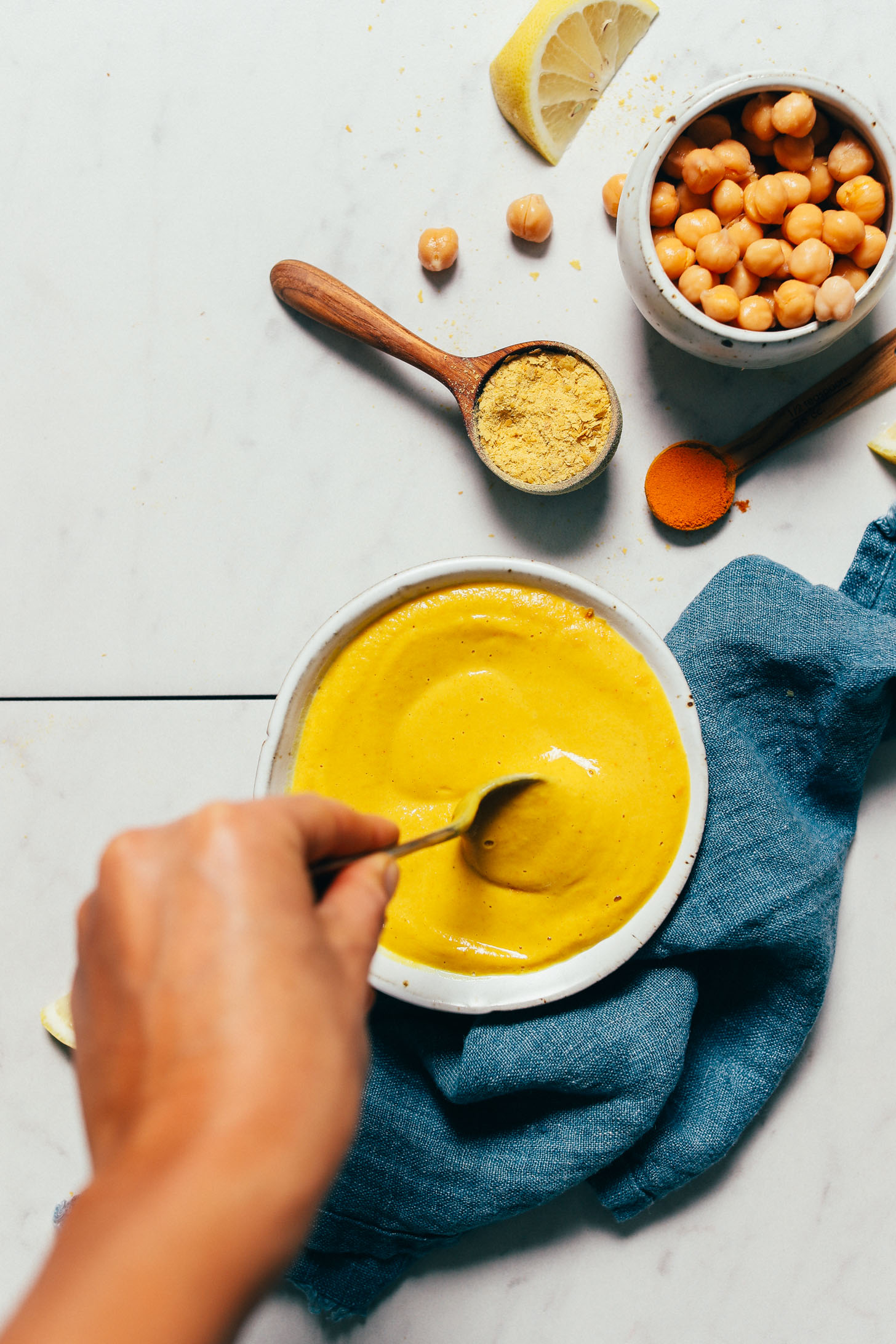 Using a spoon to stir a bowl of Liquid Gold Sauce inspired by The Whole Bowl's Thali Sauce