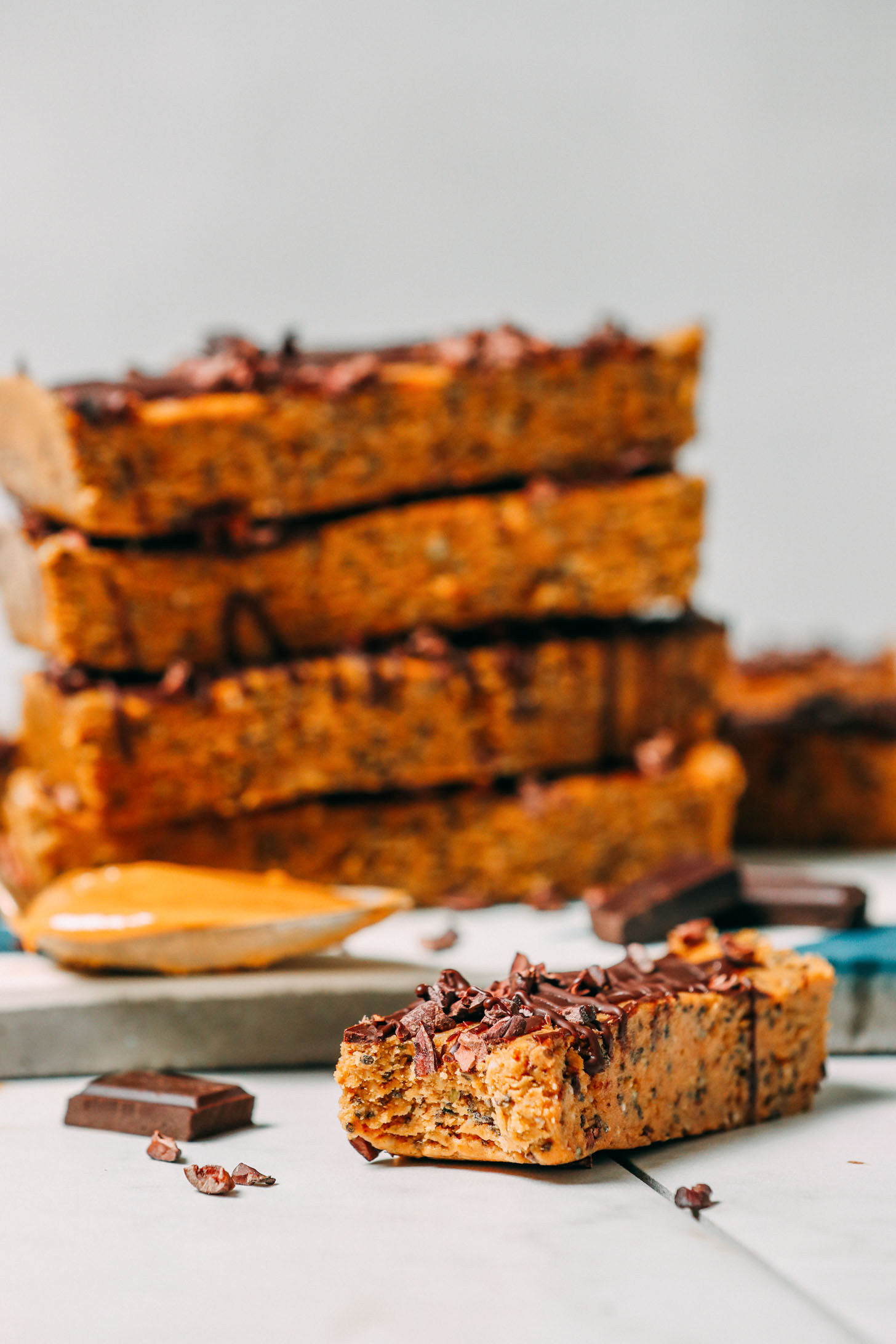 Partially eaten peanut butter protein bar resting beside a stack of the rest of the batch