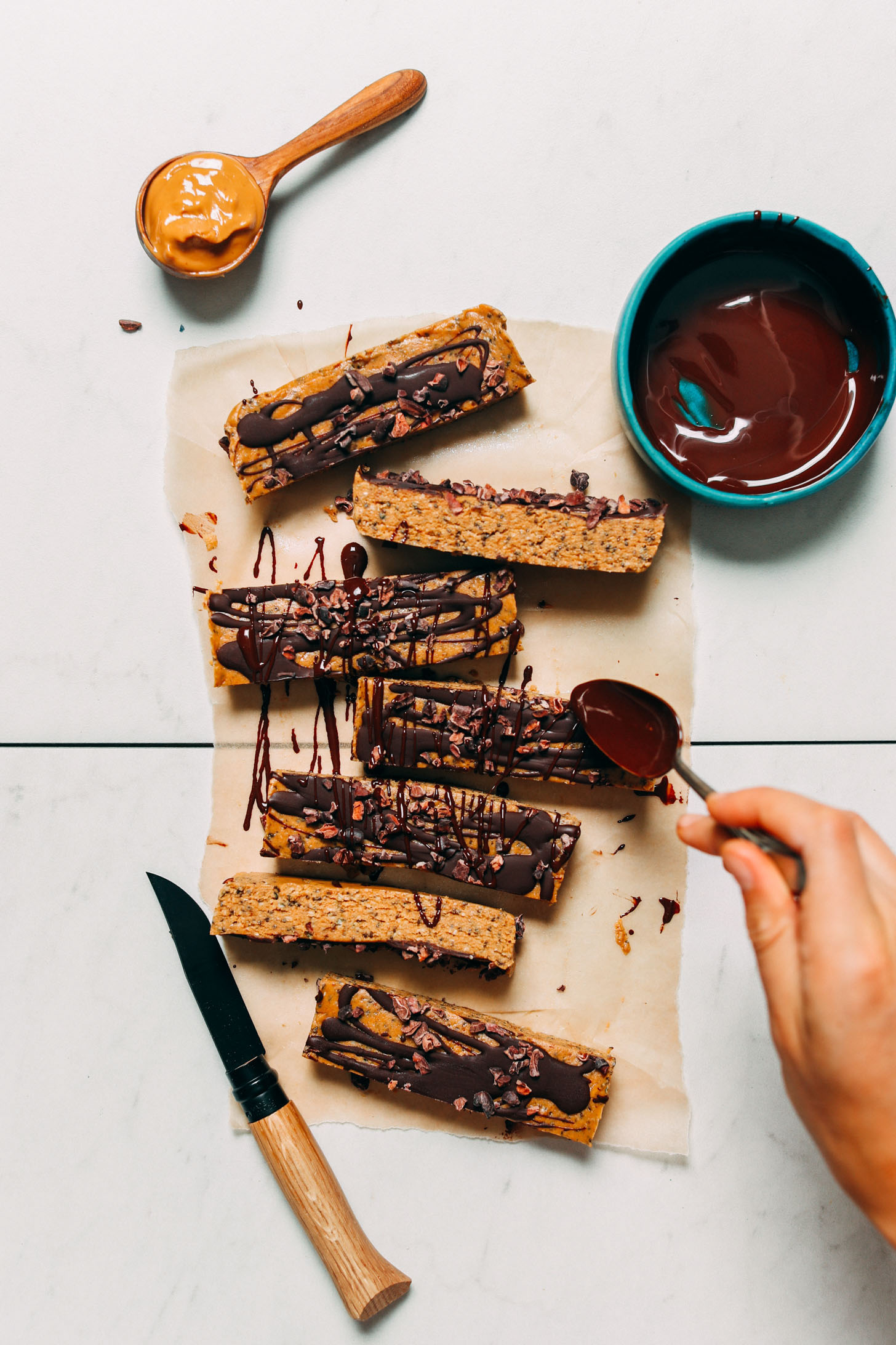 Drizzling a second layer of melted chocolate onto date-sweetened peanut butter protein bars