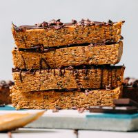 Dark chocolate and a spoonful of peanut butter resting beside homemade Peanut Butter Protein Bars