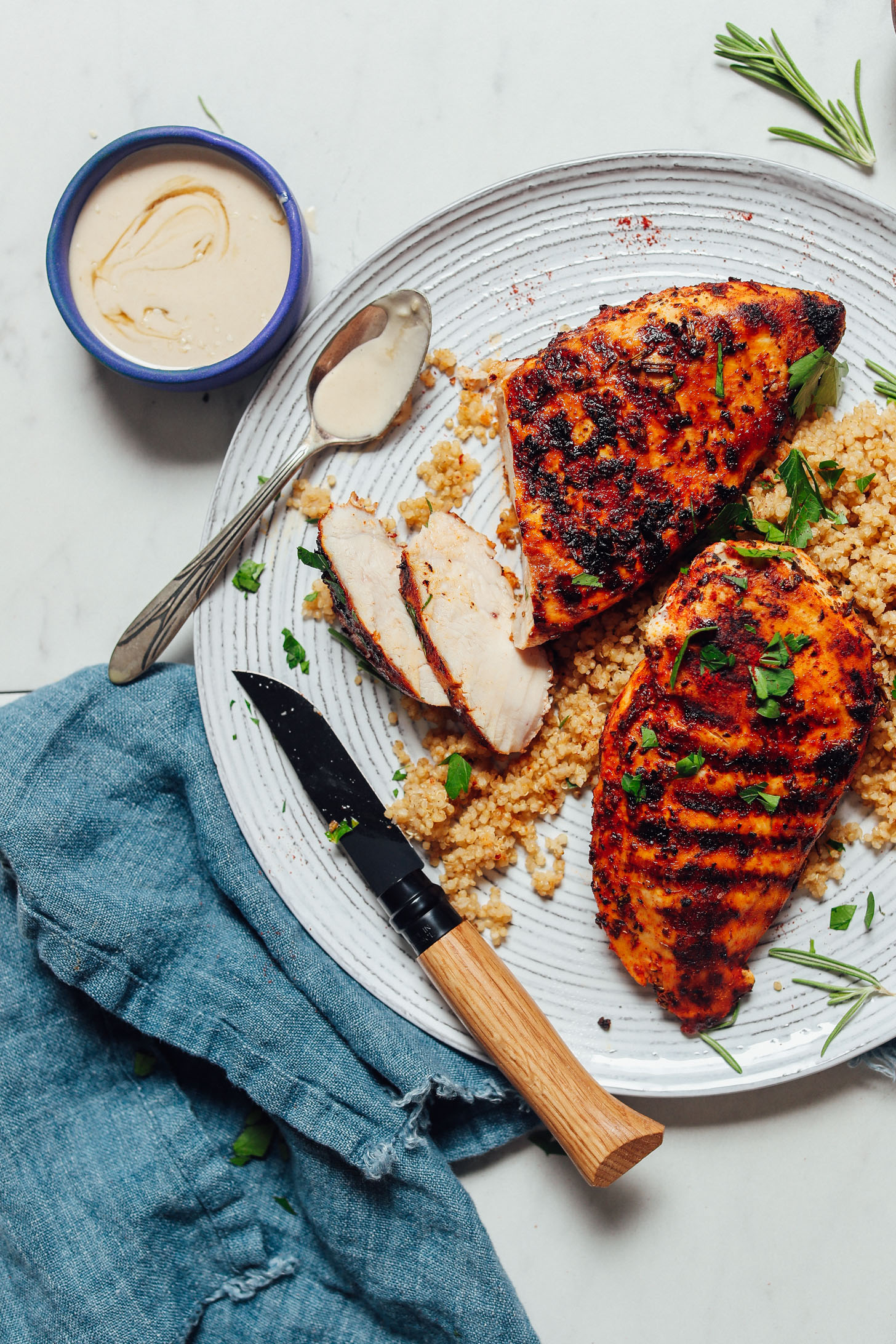 Plate of Marinated Grilled Chicken beside quinoa and a bowl of tahini sauce