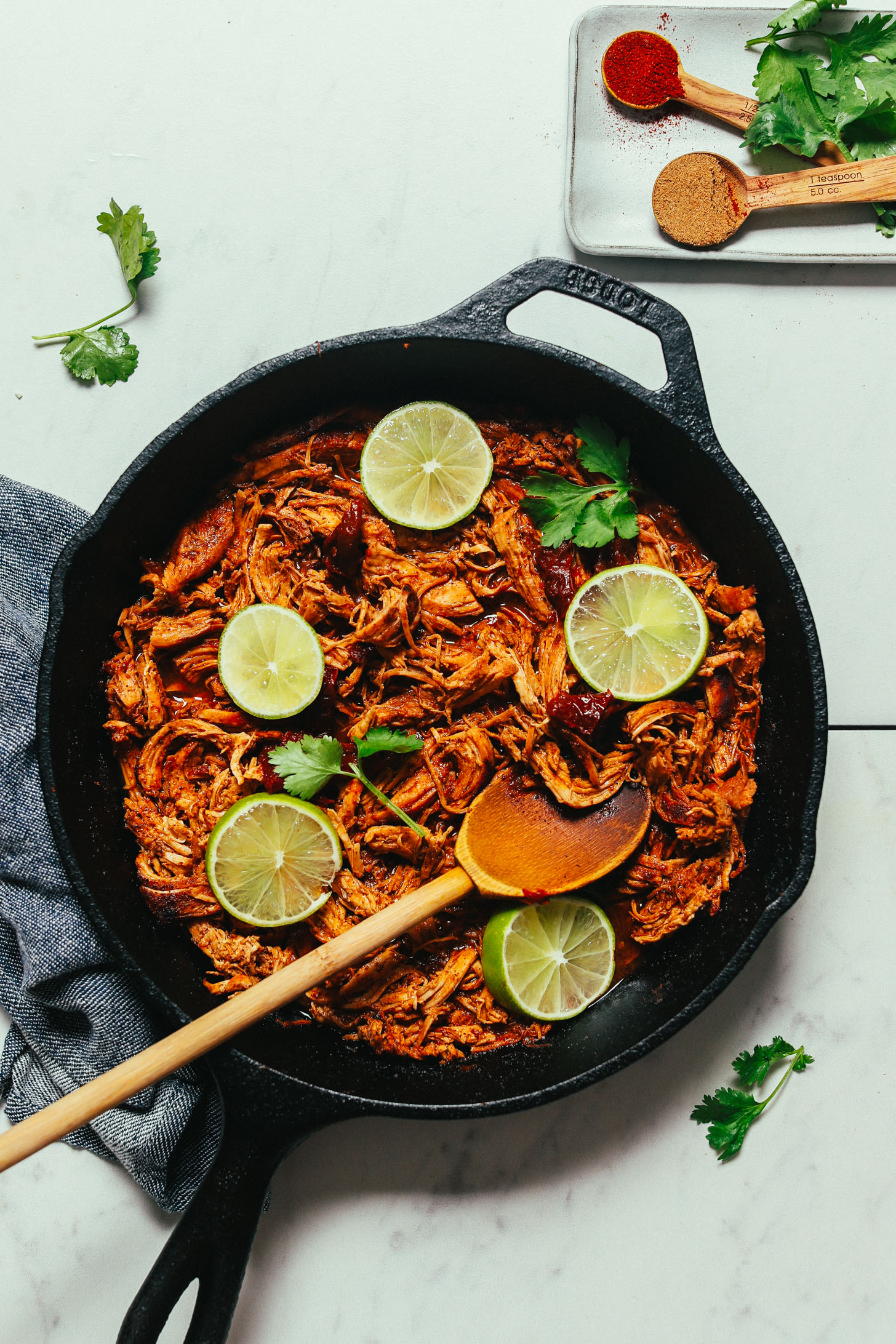 Wooden spoon in a skillet of Mexican Shredded Chicken made with chipotle peppers and lime