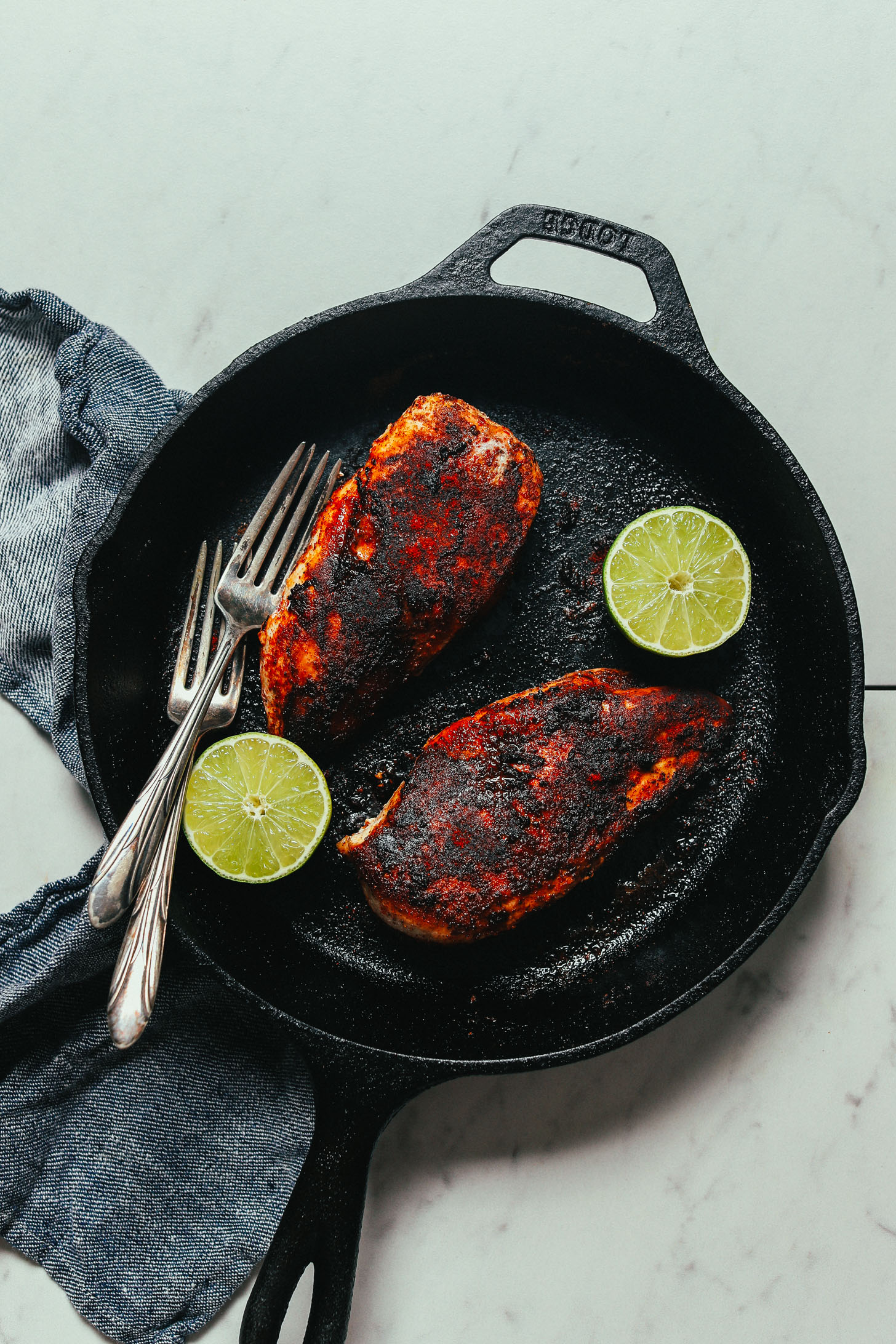 Skillet of cooked Mexican-seasoned boneless skinless chicken breasts and limes