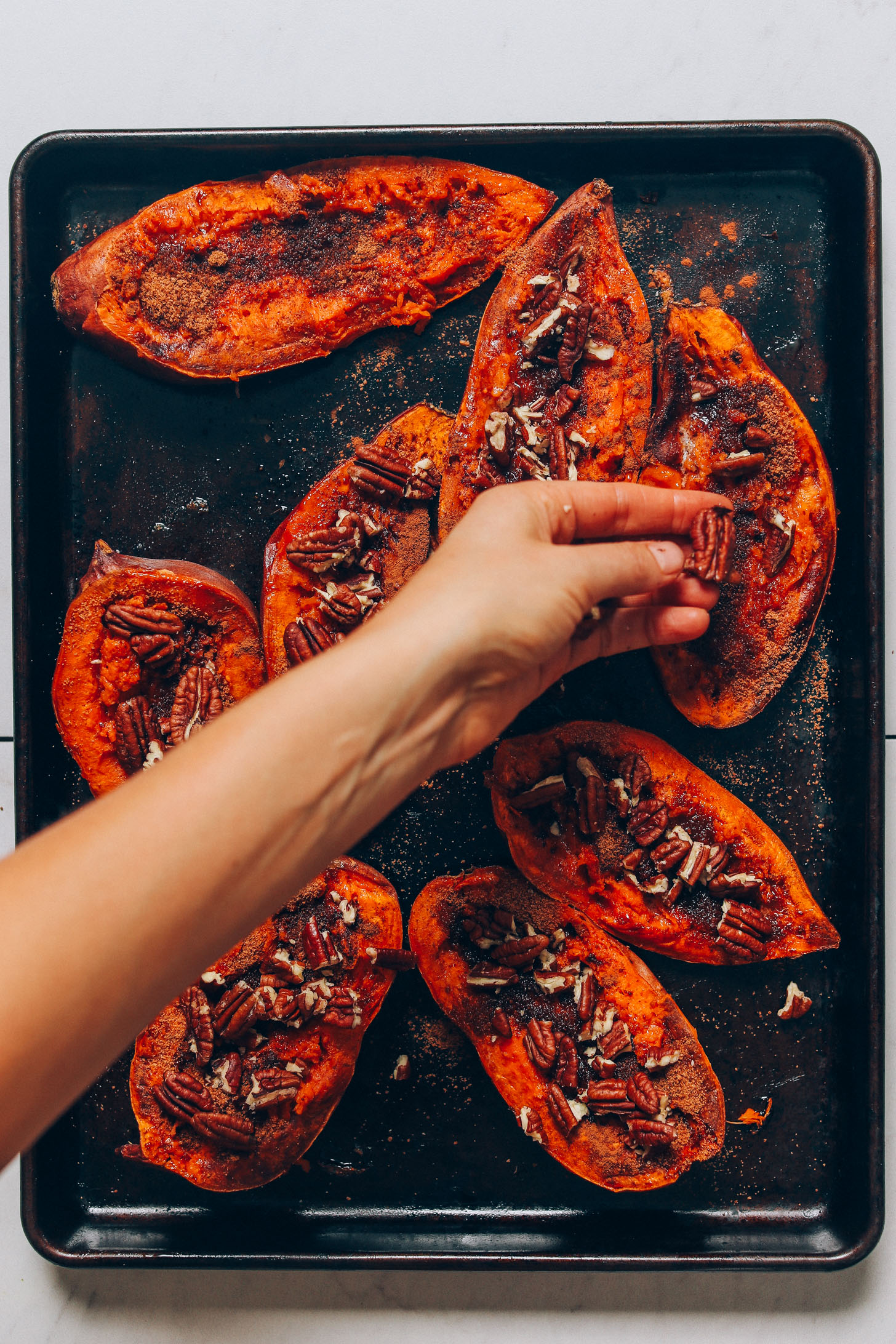 Topping Sweet Potato Casserole Boats with pecans for a delicious Thanksgiving side