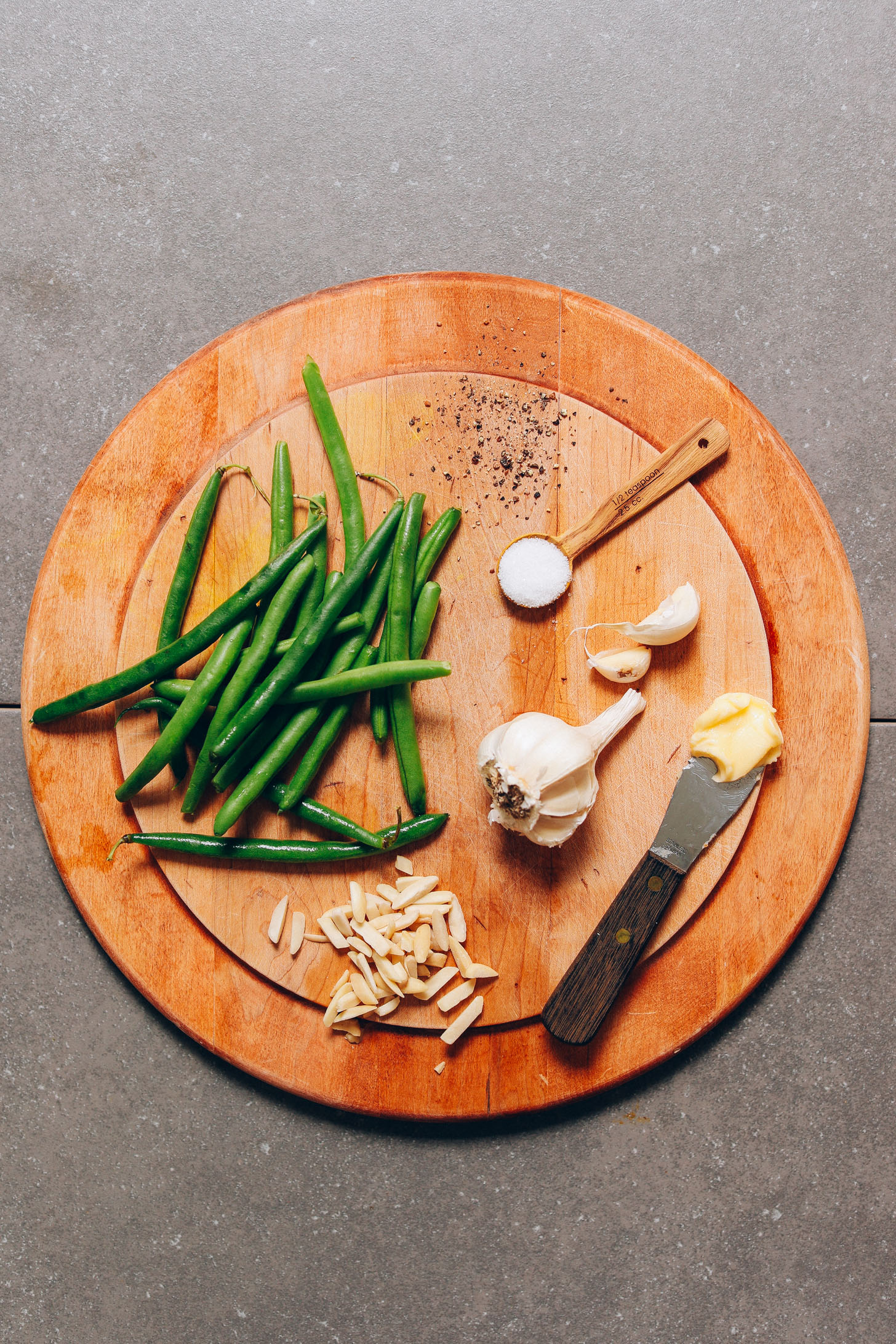 Wood cutting board with ingredients for making our easy Green Beans recipe