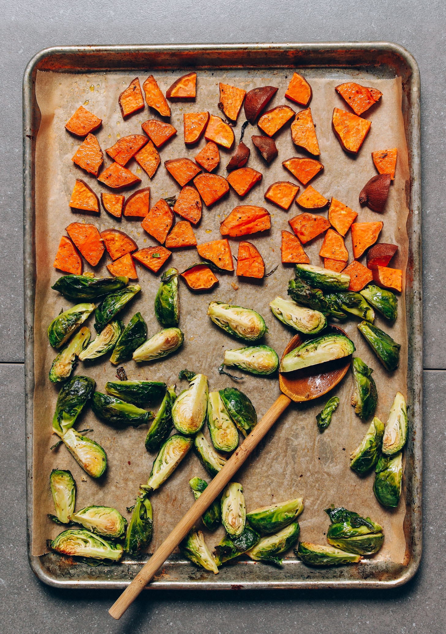 Parchment-lined baking sheet of roasted sweet potatoes and Brussels sprouts for our Fall Breakfast Hash recipe