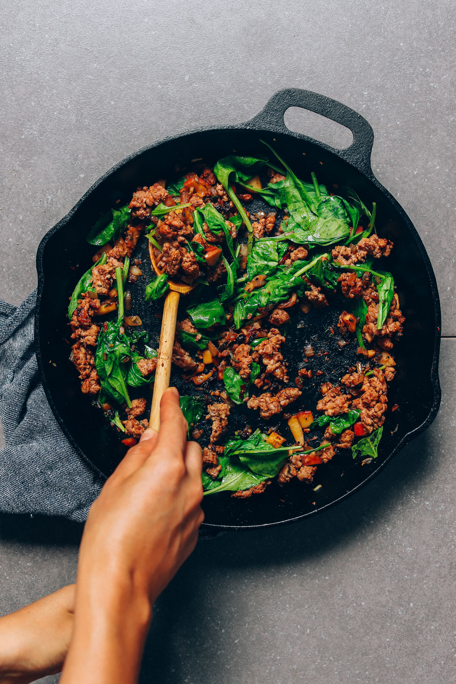 Sautéing spinach and sausage in a large skillet for our Fall Sweet Potato Breakfast Hash recipe