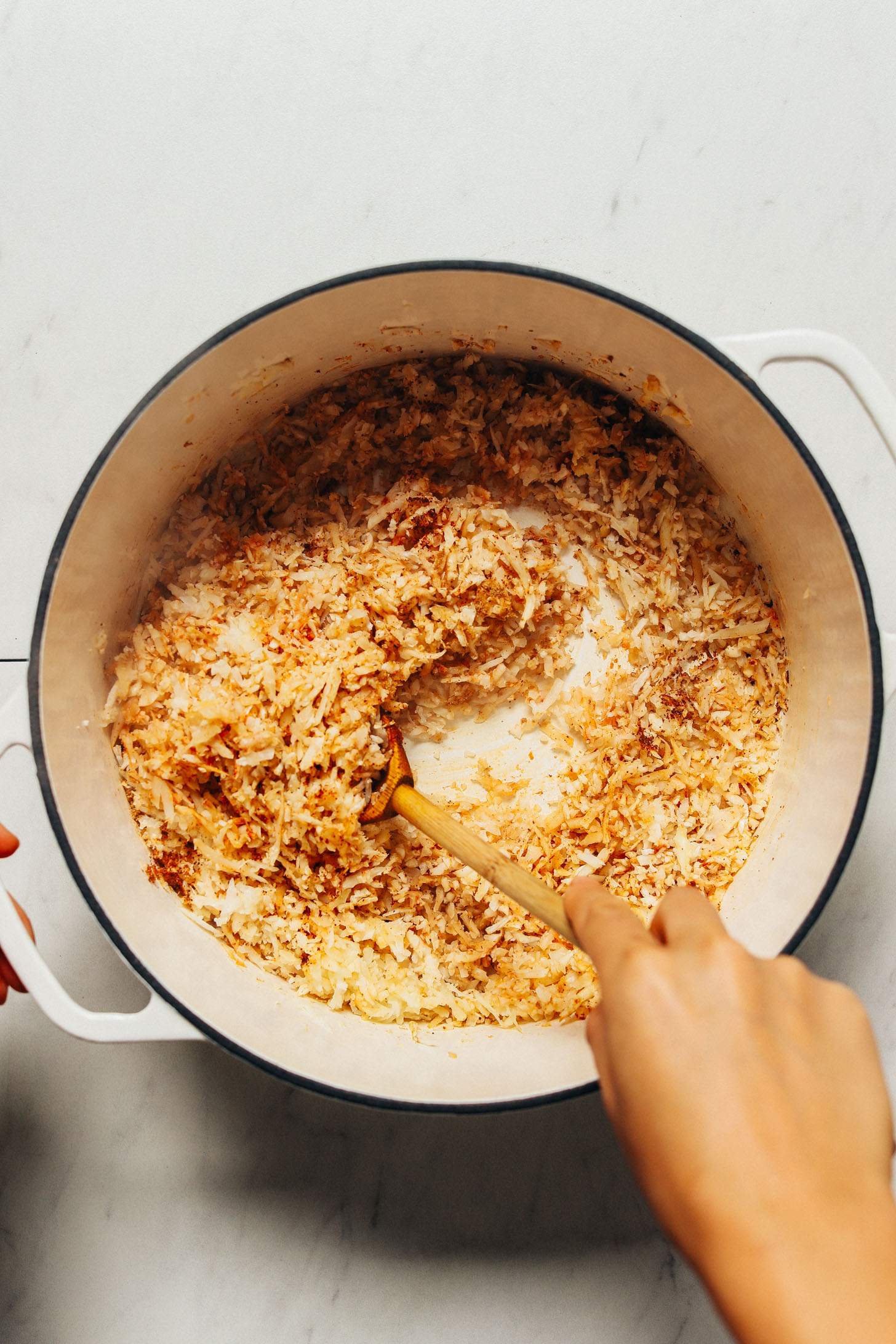Using a wooden spoon to cook a pot of cauliflower rice for our Grain-Free Burrito Bowls recipe