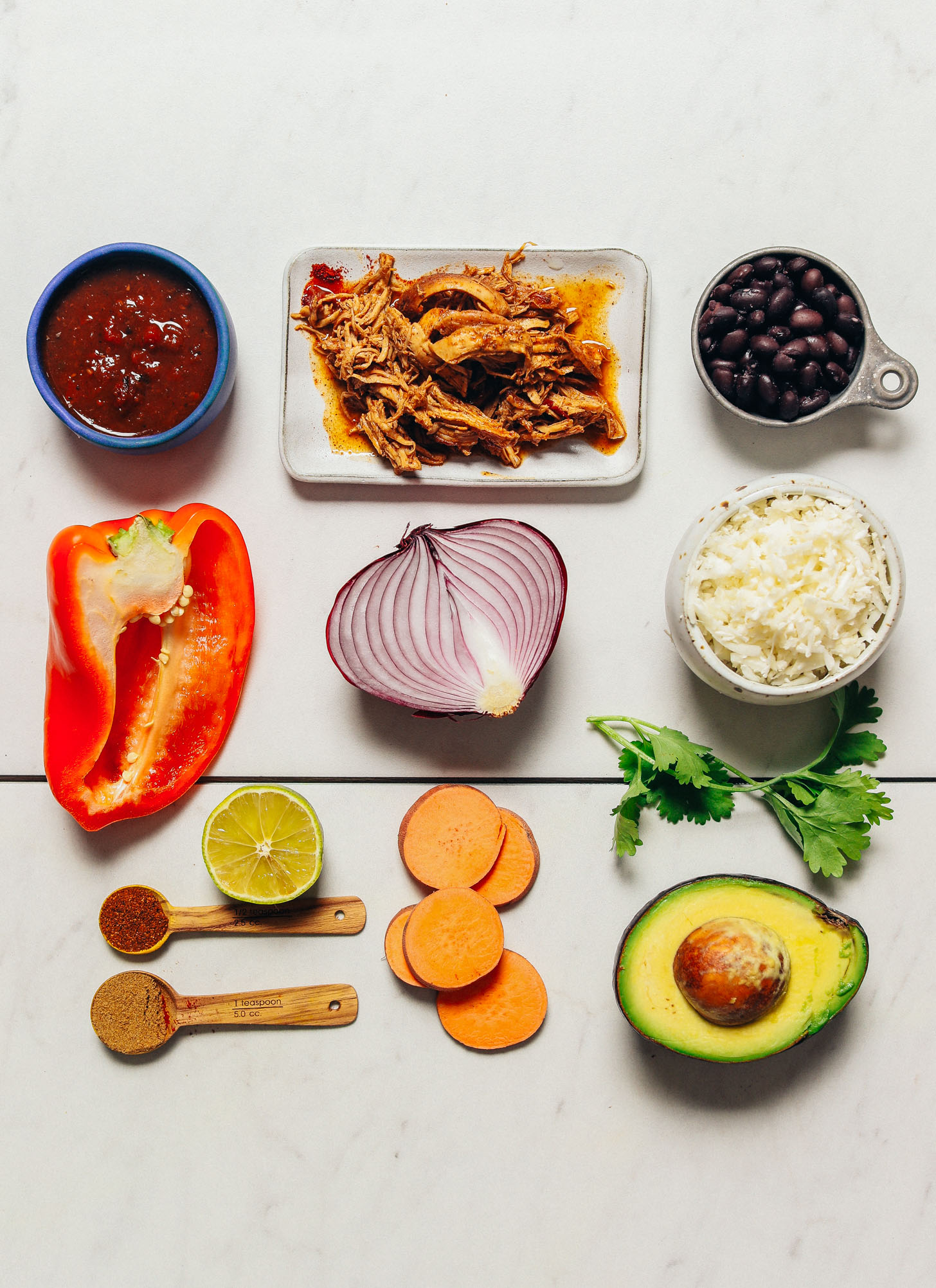 Shredded chicken, black beans, cauliflower rice, and other ingredients for making healthy Grain-Free Burrito Bowls