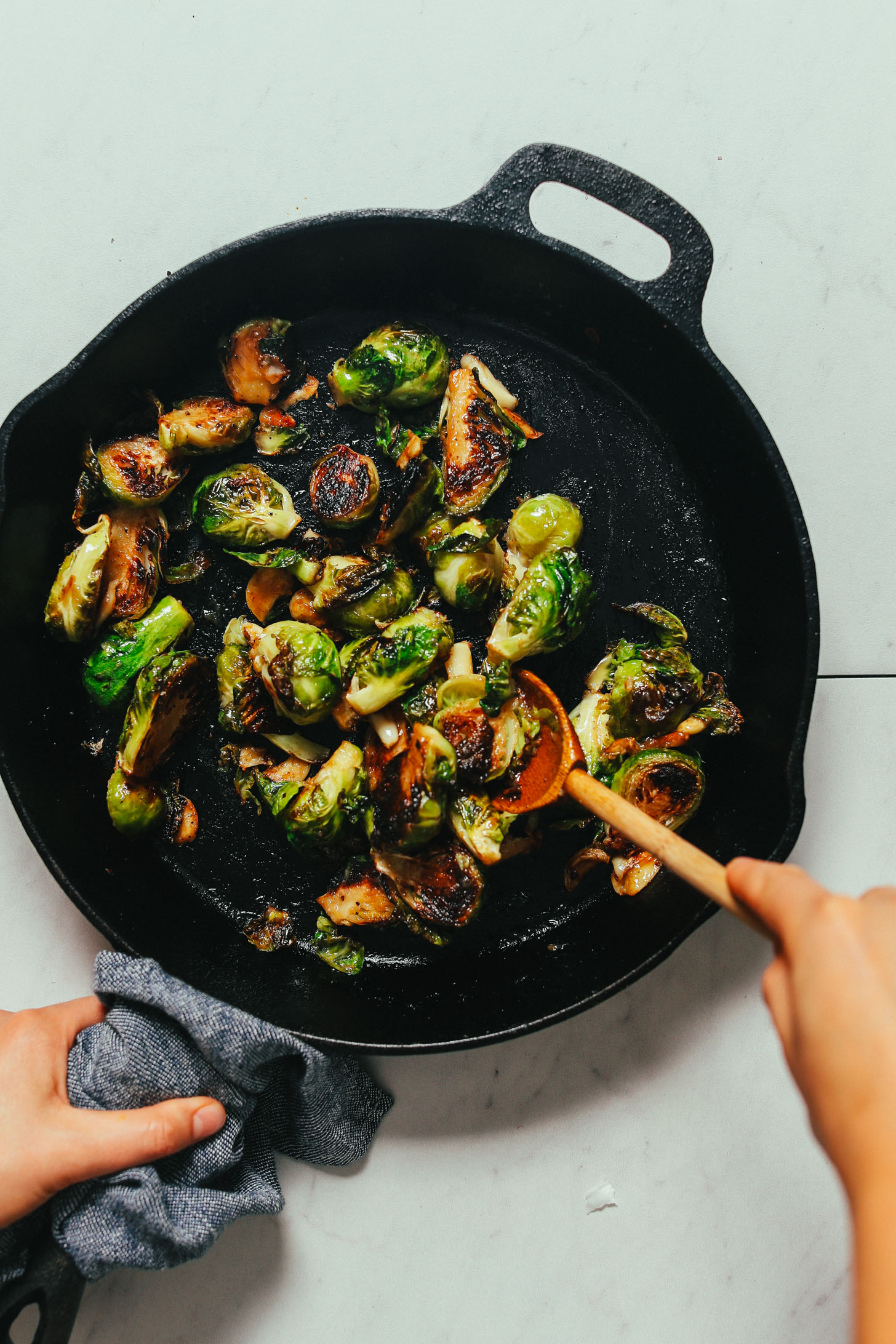 Stirring a pan of crispy Roasted Brussels Sprouts made with a miso glaze