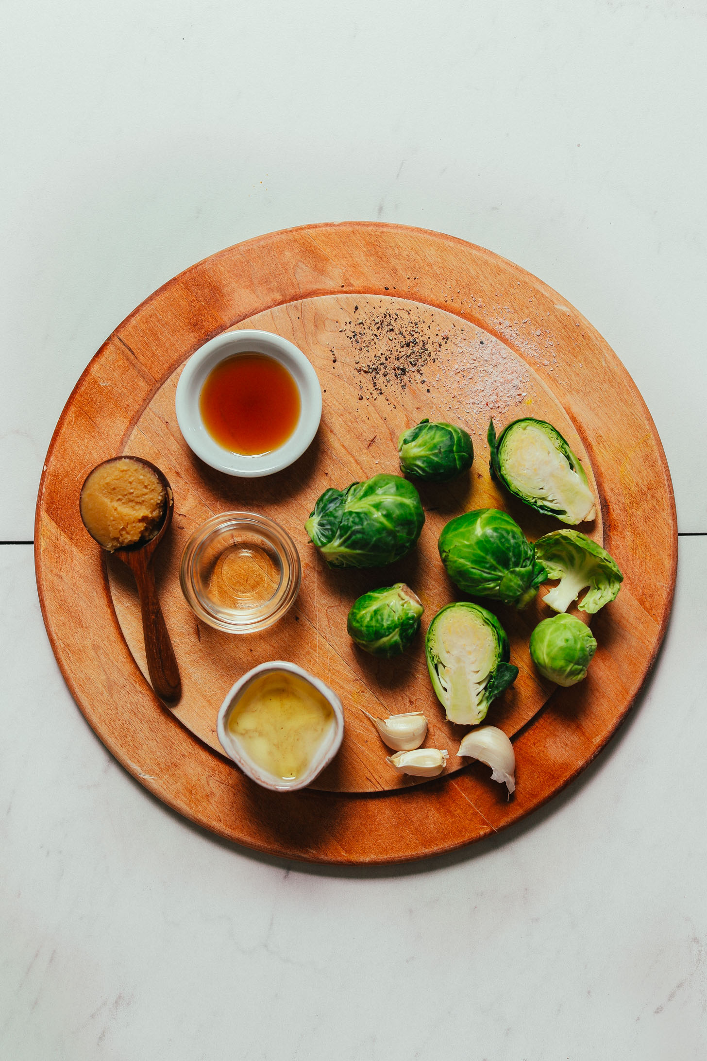 Wood cutting board with ingredients for making our easy Roasted Brussels Sprouts recipe