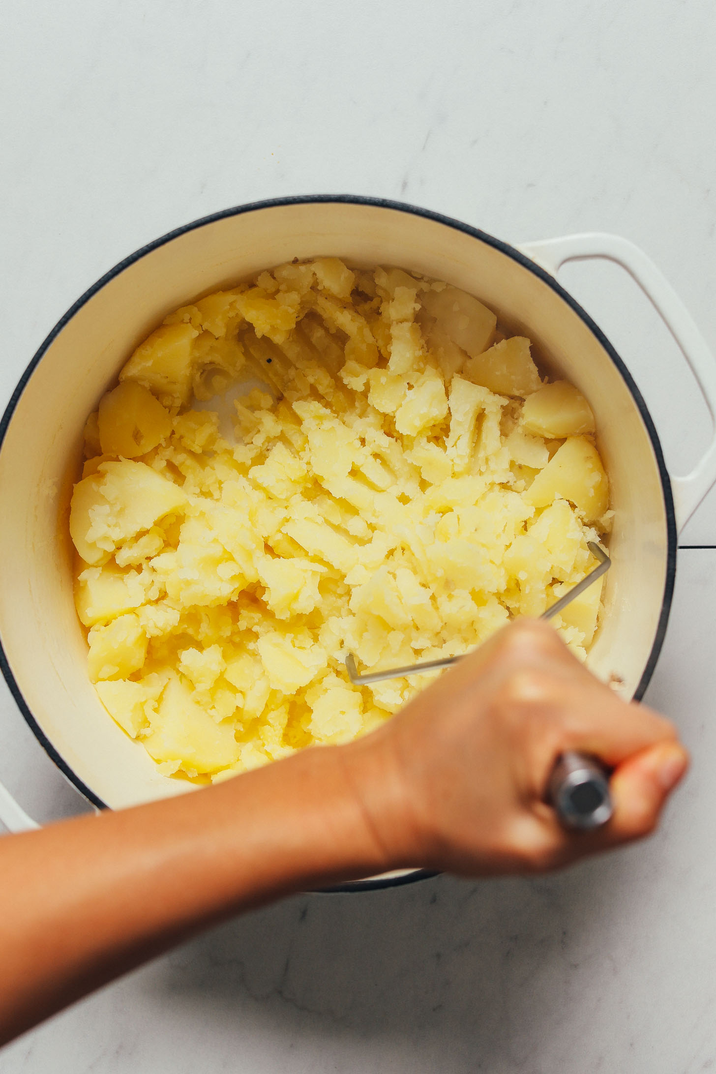 Using a potato masher to make the Best Mashed Potatoes for Thanksgiving