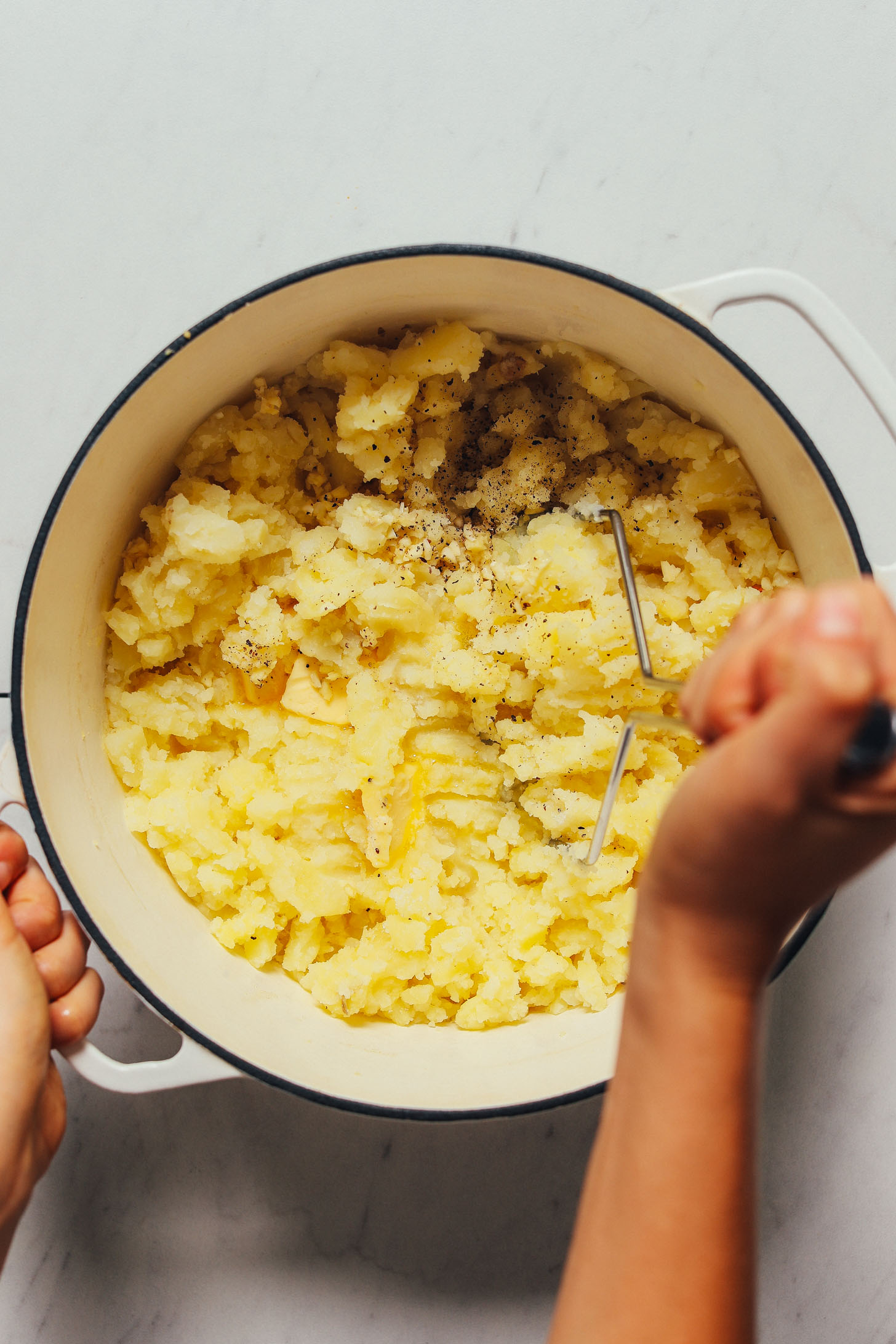 Using a potato masher to show How to Make Mashed Potatoes